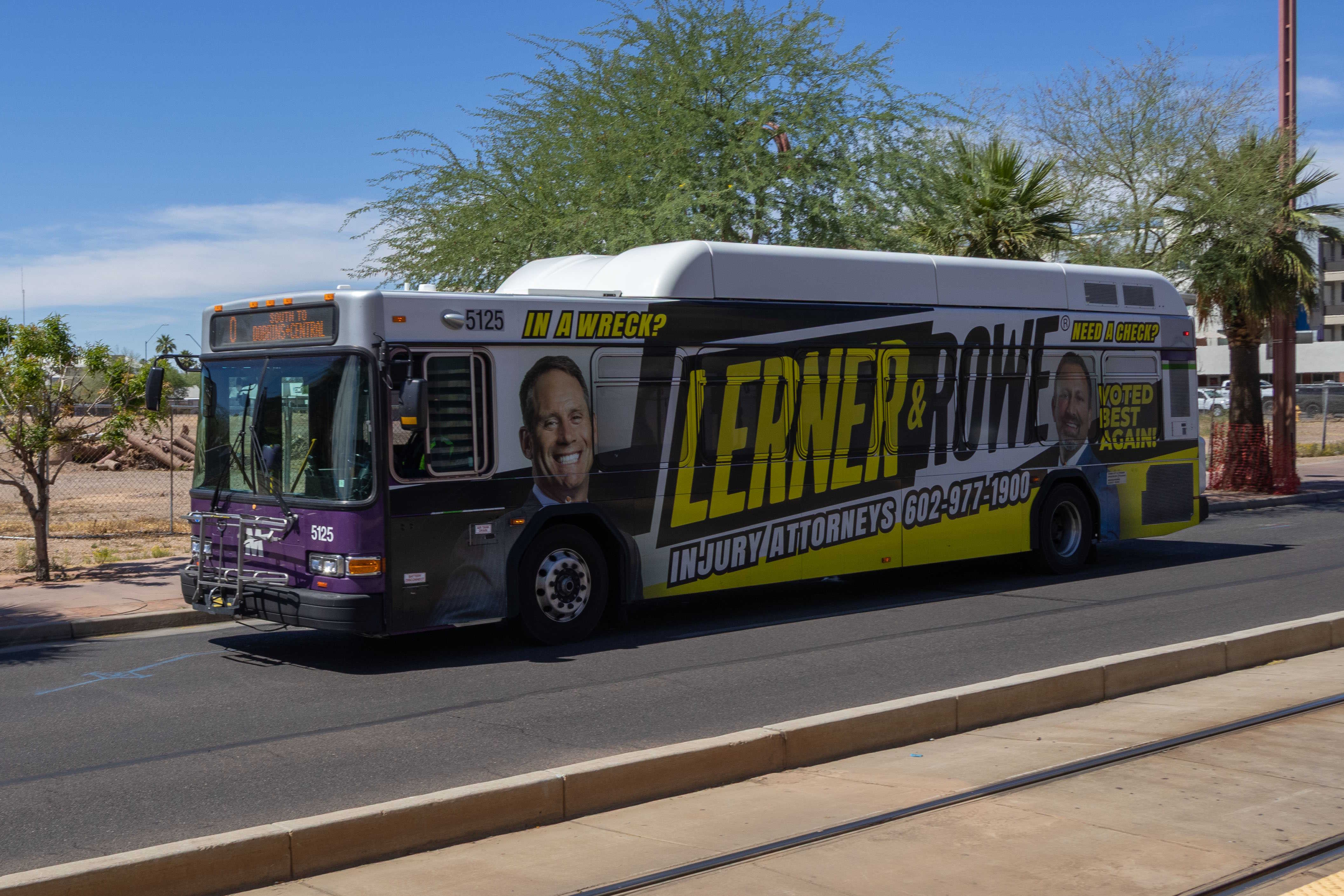 A white and gray Valley Metro bus, with purple and green accent colors, number 5125, traveling southbound on Central Avenue in Phoenix on route 0 to Central Avenue and Dobbins Road