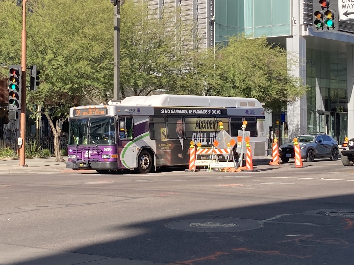 A white and gray Valley Metro bus, with purple and green accent colors, number 5238, traveling westbound on Van Buren Street in Phoenix on route 0A to Baseline and Central