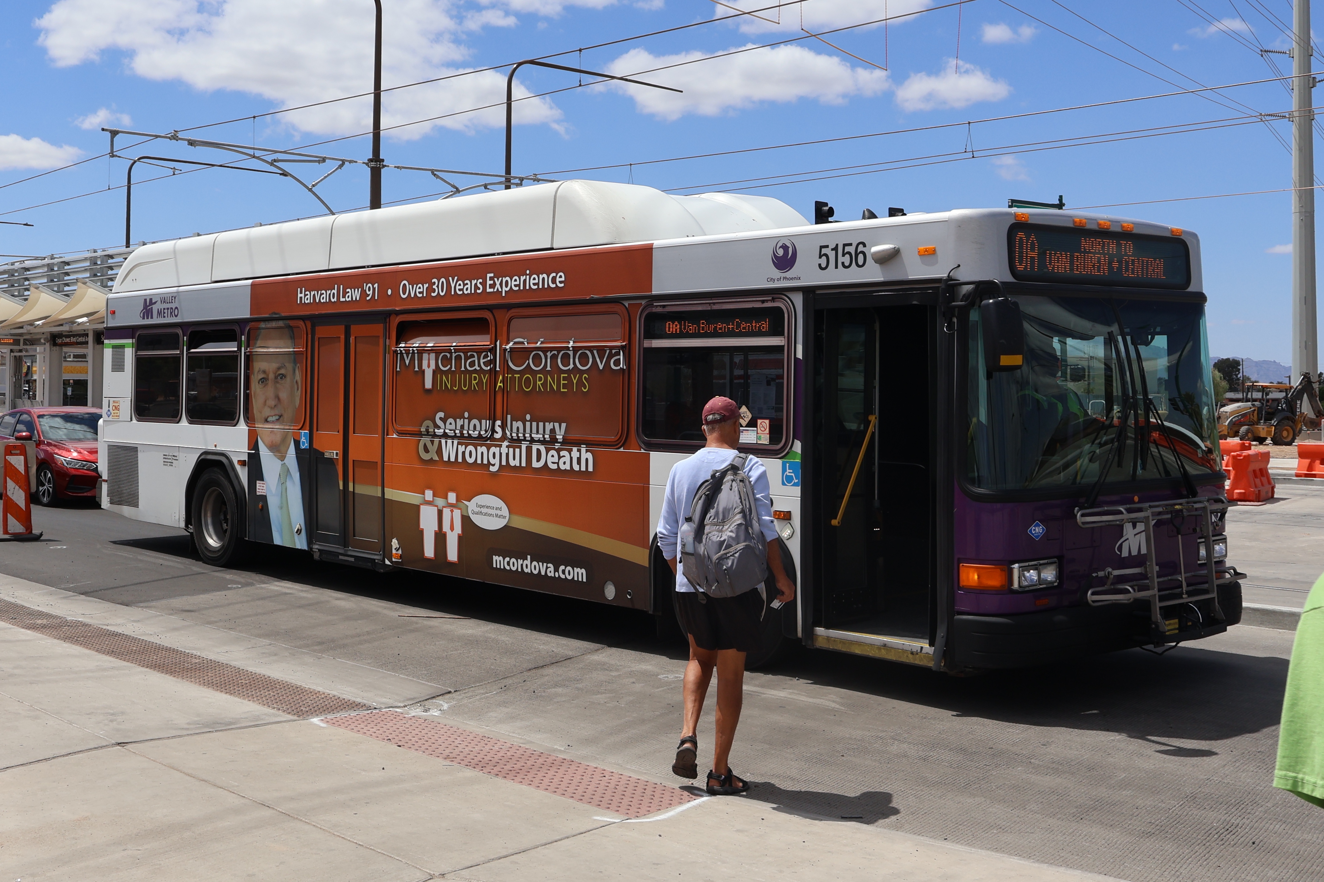 A white and gray Valley Metro bus, with purple and green accent colors, number 5156, traveling northbound on Central Avenue in Phoenix on route 0A to Van Buren and Central