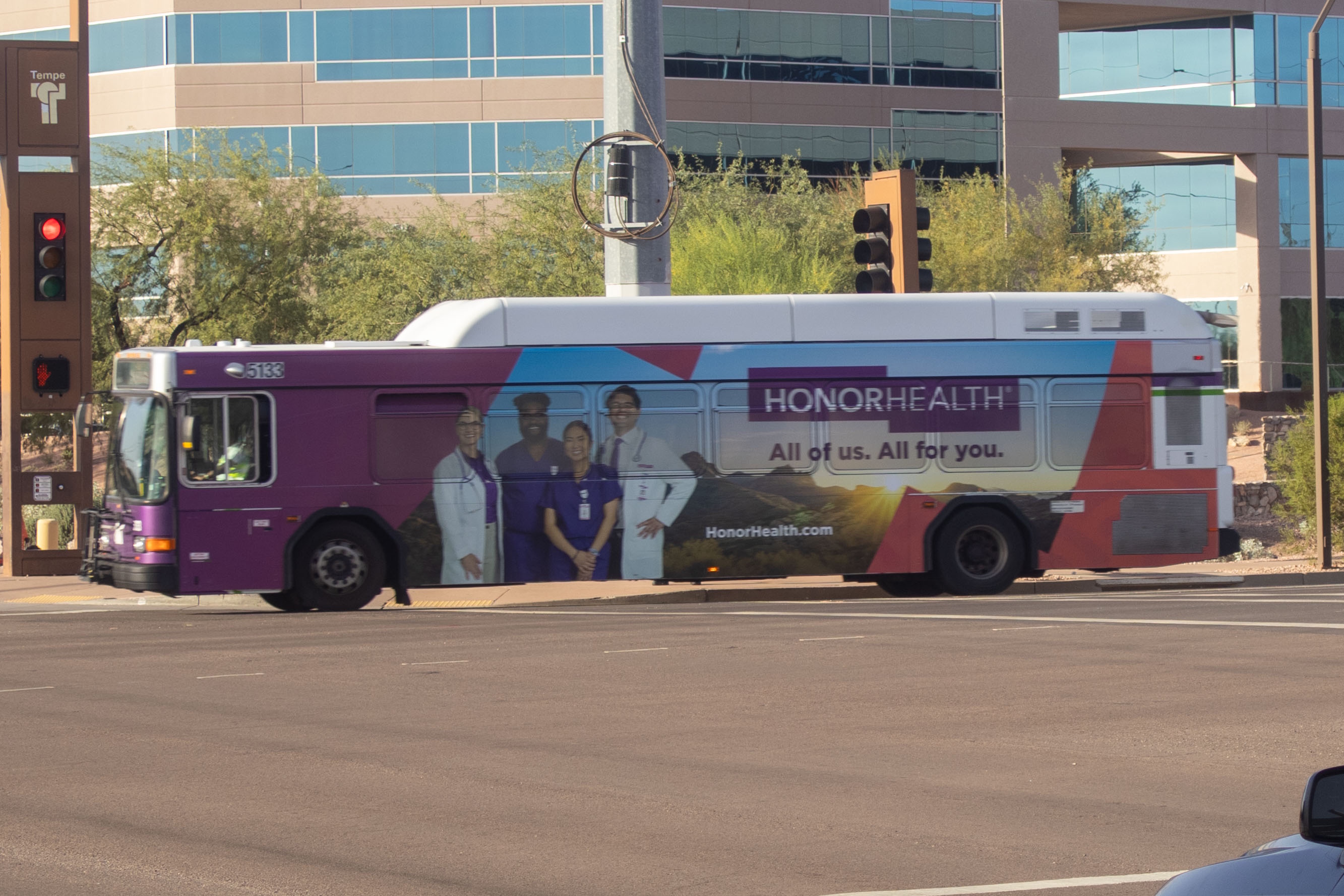 A white and gray Valley Metro bus, with purple and green accent colors, number 5133, traveling southbound on Priest Drive in Tempe on route 1 to Greg Station Central Station