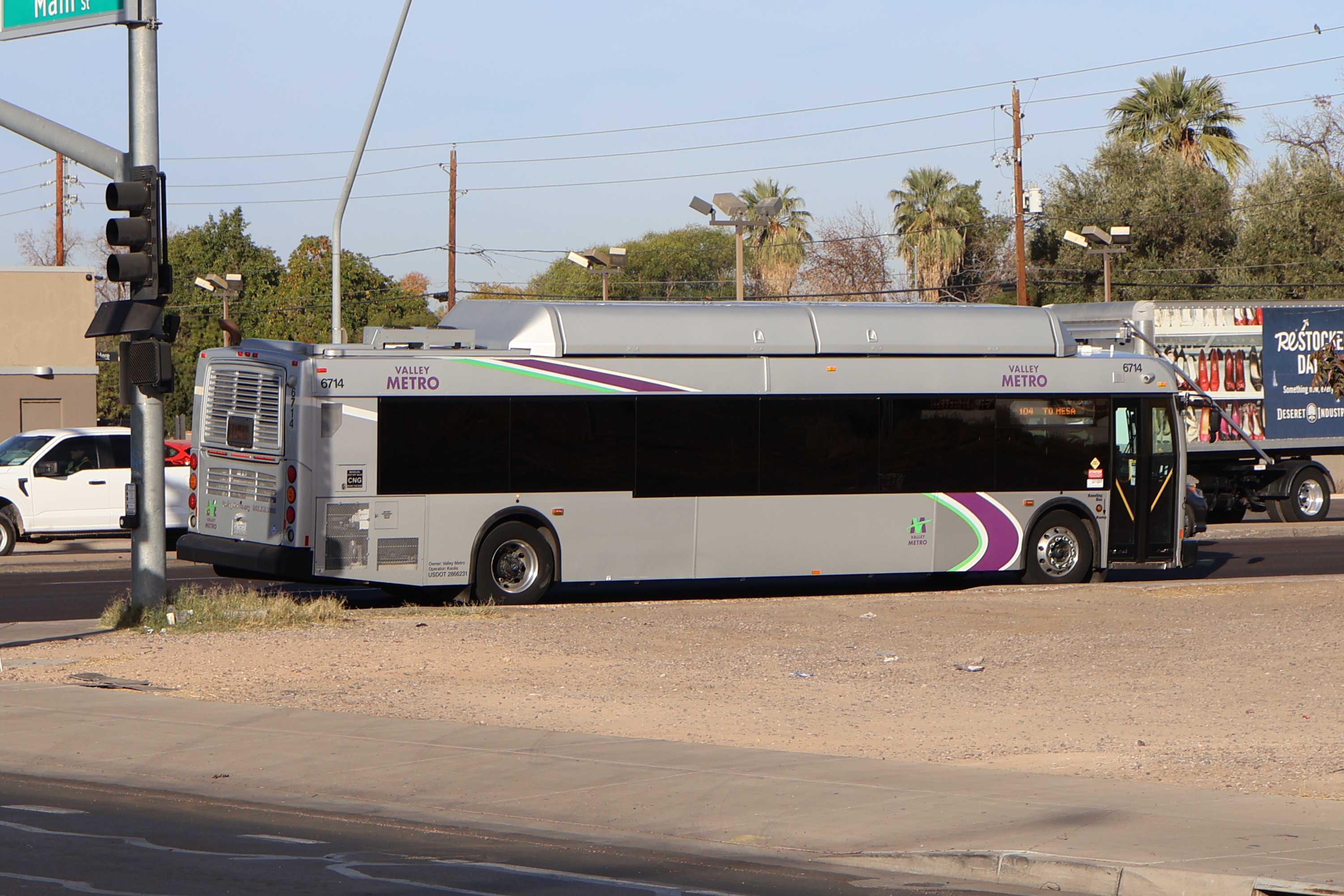 A silver Valley Metro bus, with green, purple, and white stripes, number 6714, traveling northbound on Alma School Road in Mesa on route 104 to Mesa Riverview