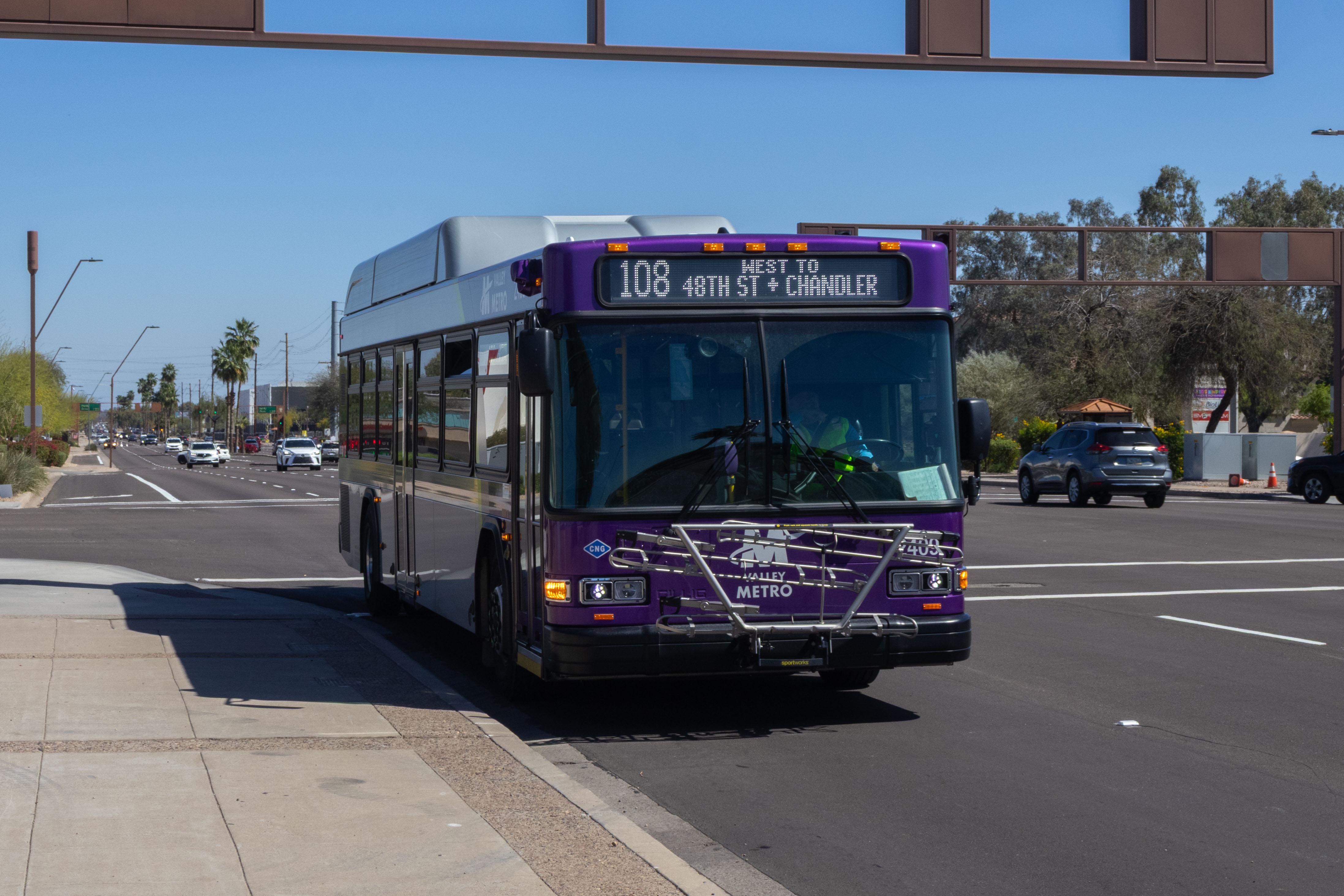 A gray and purple Valley Metro bus, with a green stripe, number 2409, traveling westbound on Elliot Road in Tempe on route 108 to 48th Street and Chandler Boulevard