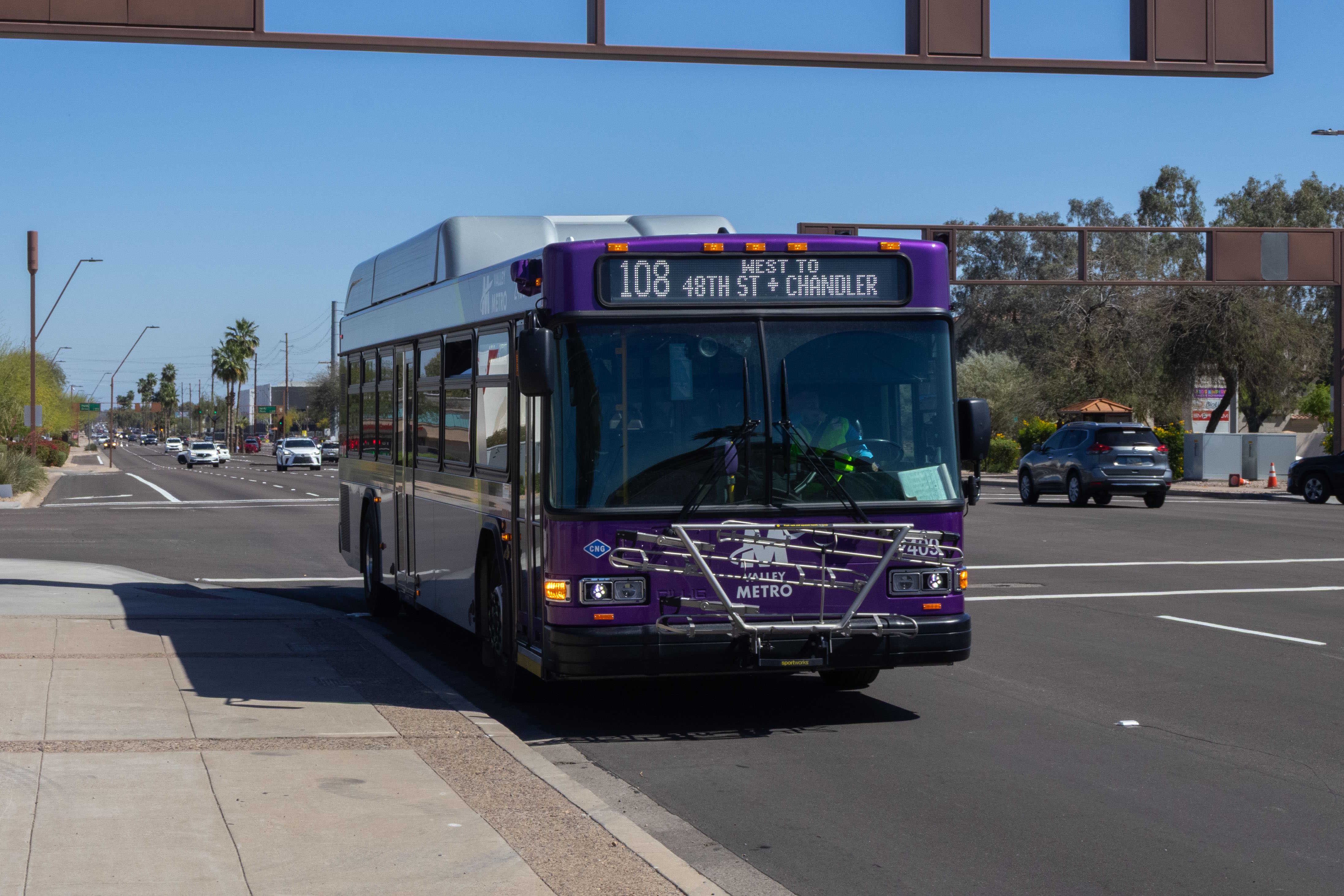 A gray and purple Valley Metro bus, with a green stripe, number 2409, traveling westbound on Elliot Road in Tempe on route 108 to 48th Street and Chandler Boulevard