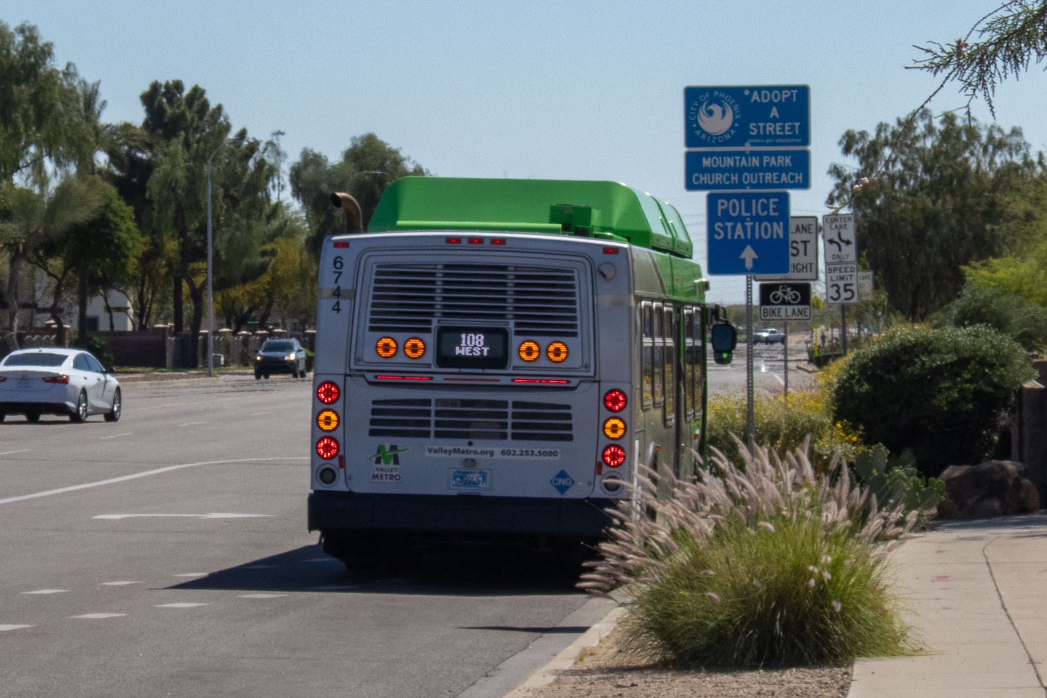 A gray and green Valley Metro bus, with a purple and white stripe, number 6744, traveling southbound on 48th Street in Phoenix on route 108 to 48th Street and Chandler Boulevard