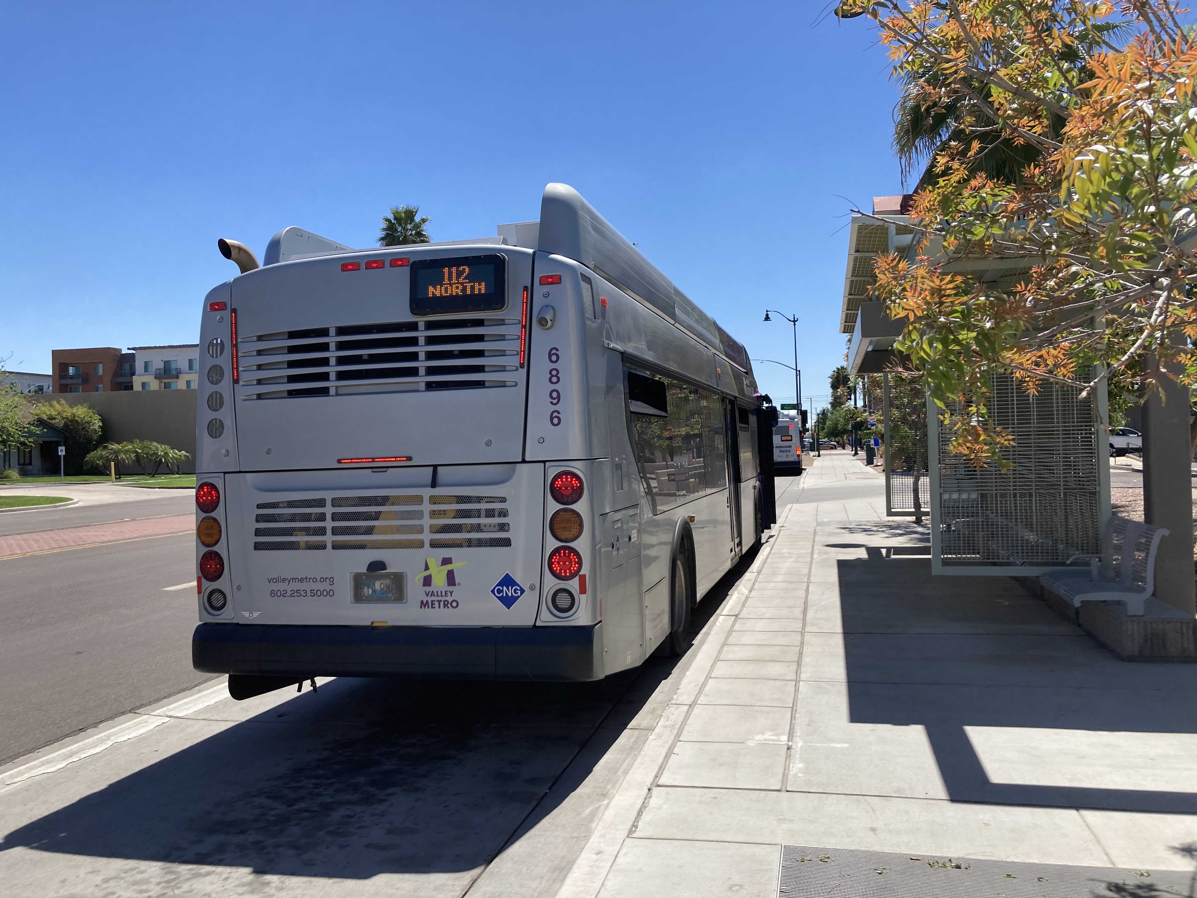 A gray and purple Valley Metro bus, with a green stripe, number 6896, at Centennial Way and Main Street in Mesa on route 112 to Centennial Way and Main Street