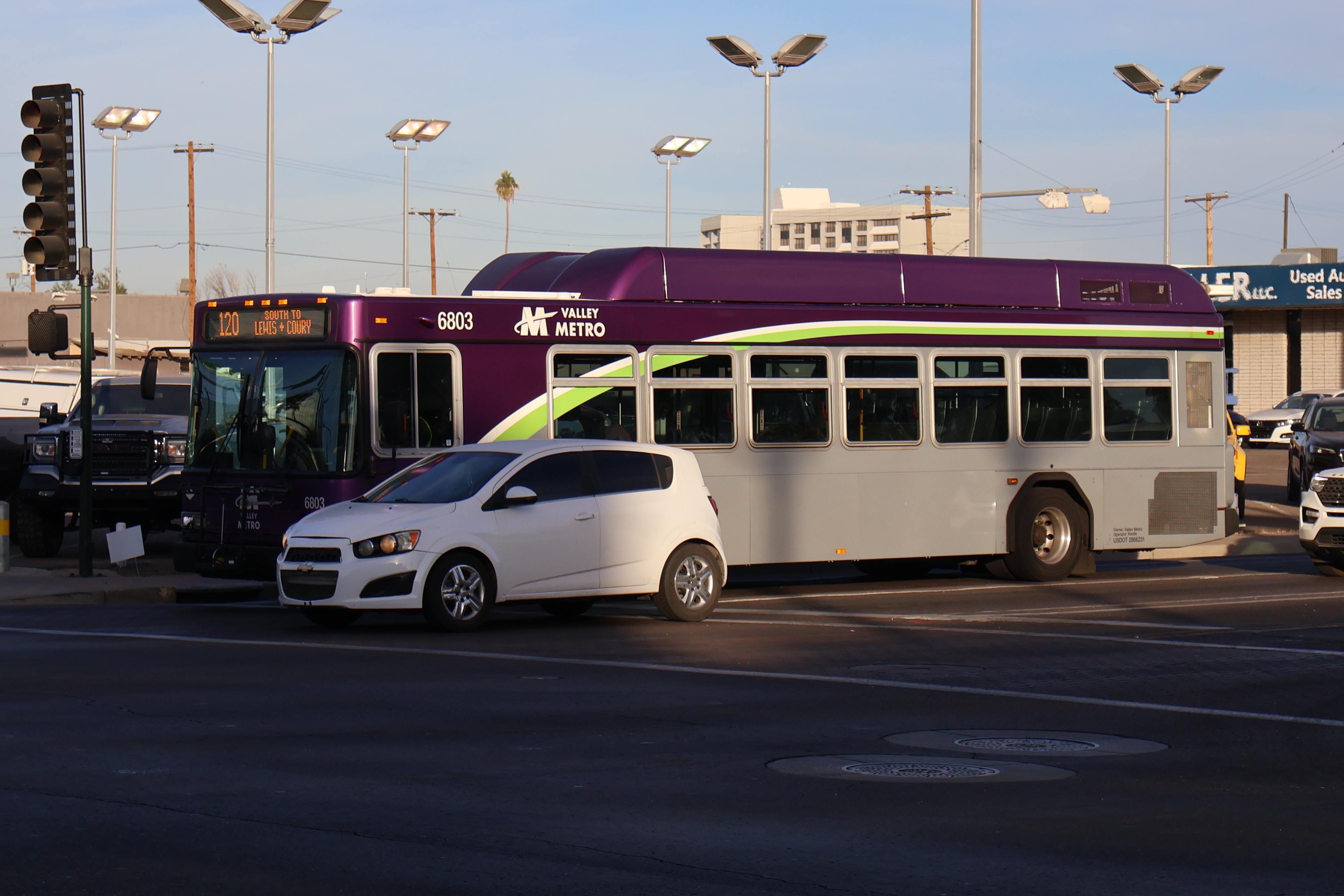 A gray and purple Valley Metro bus with a white and green stripe, number 6803, traveling southbound on Mesa Drive in Mesa on route 120 to Lewis and Coury Avenue