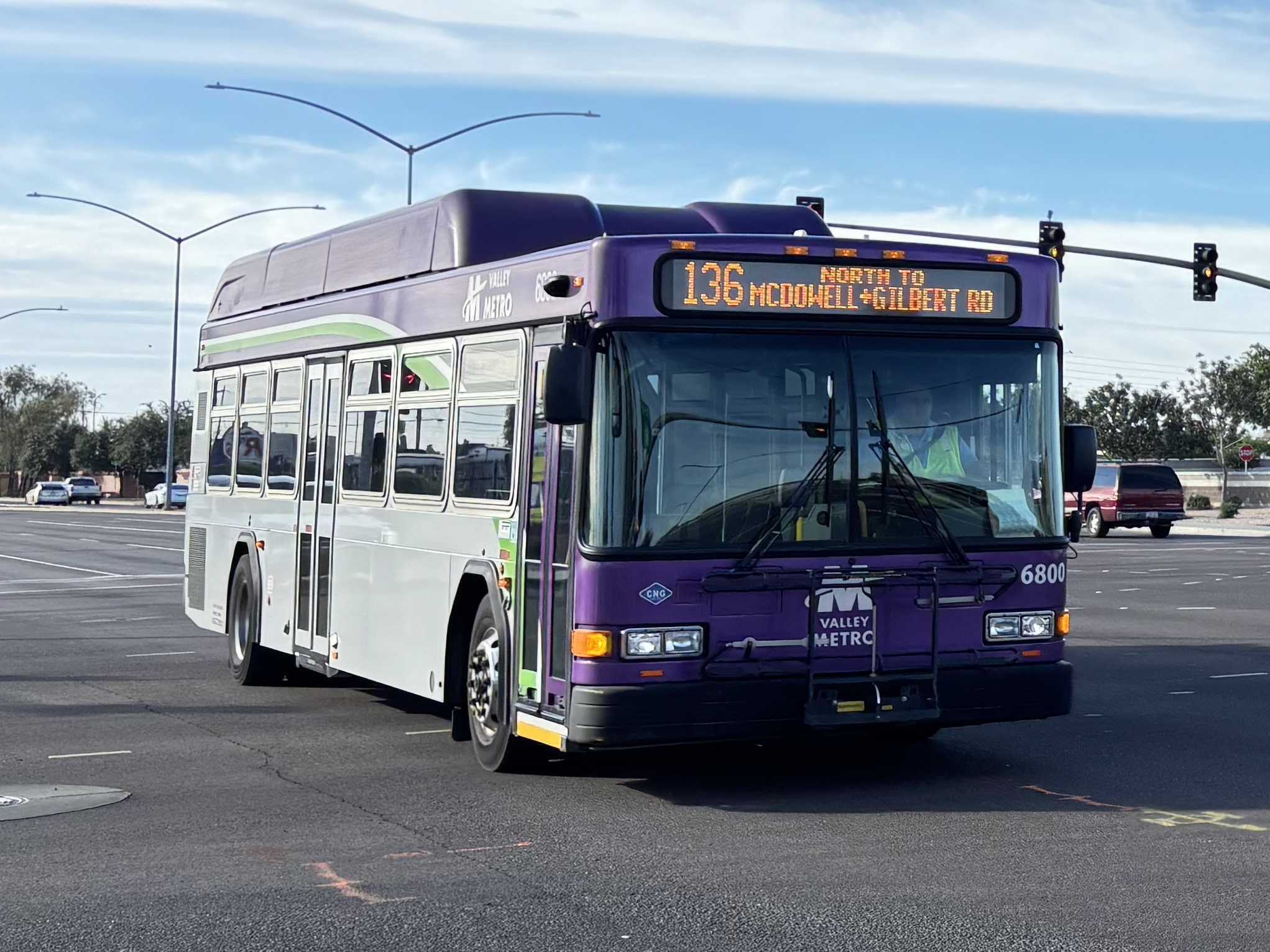 A gray and purple Valley Metro bus, with a white and green stripe, number 6800, traveling northbound on Gilbert Road in Mesa on route 136 to Gilbert Road and McDowell Road