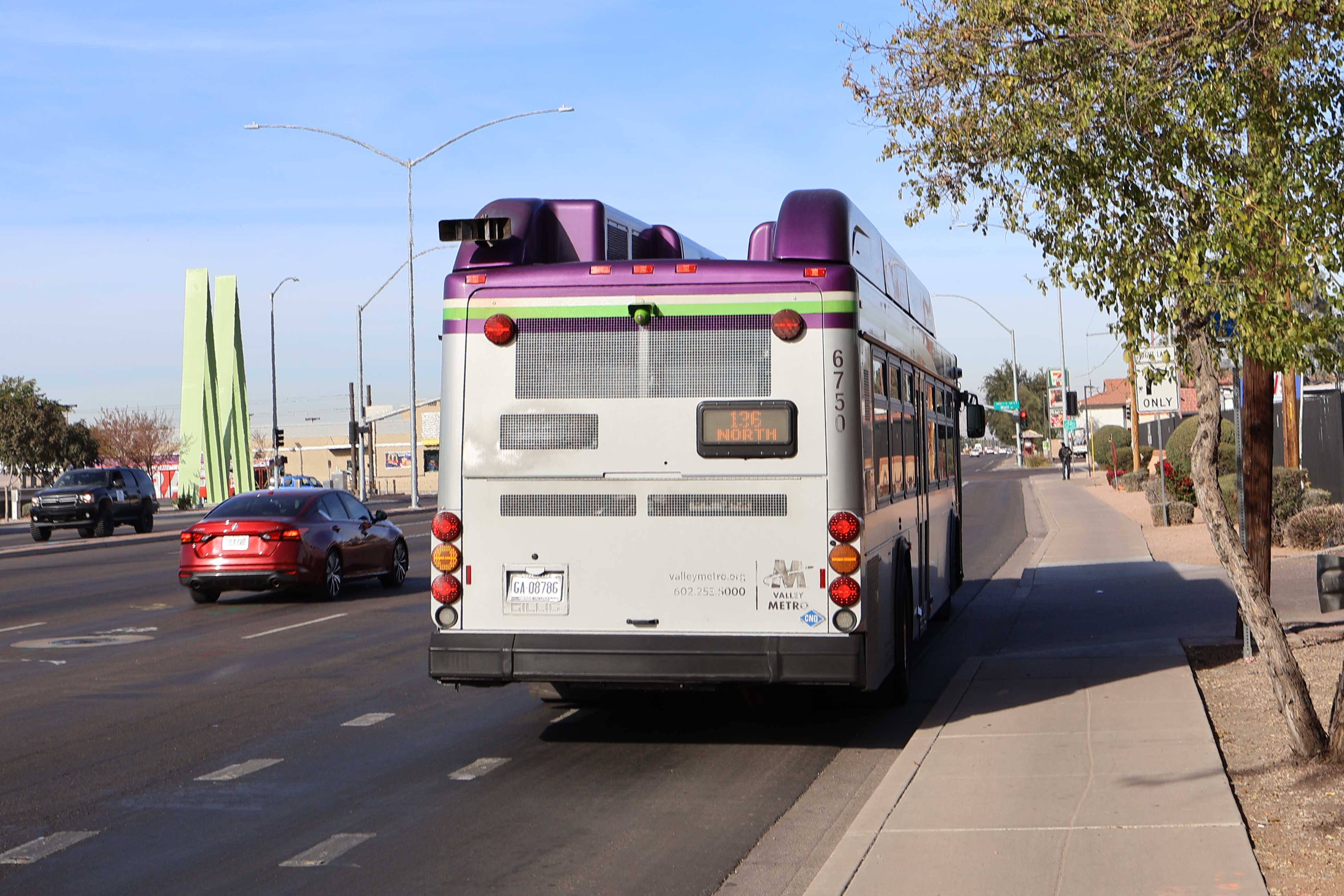 A gray and purple Valley Metro bus, with a white and green stripe, number 6750, traveling northbound on Gilbert Road in Gilbert on route 136 to Gilbert Road and McDowell Road