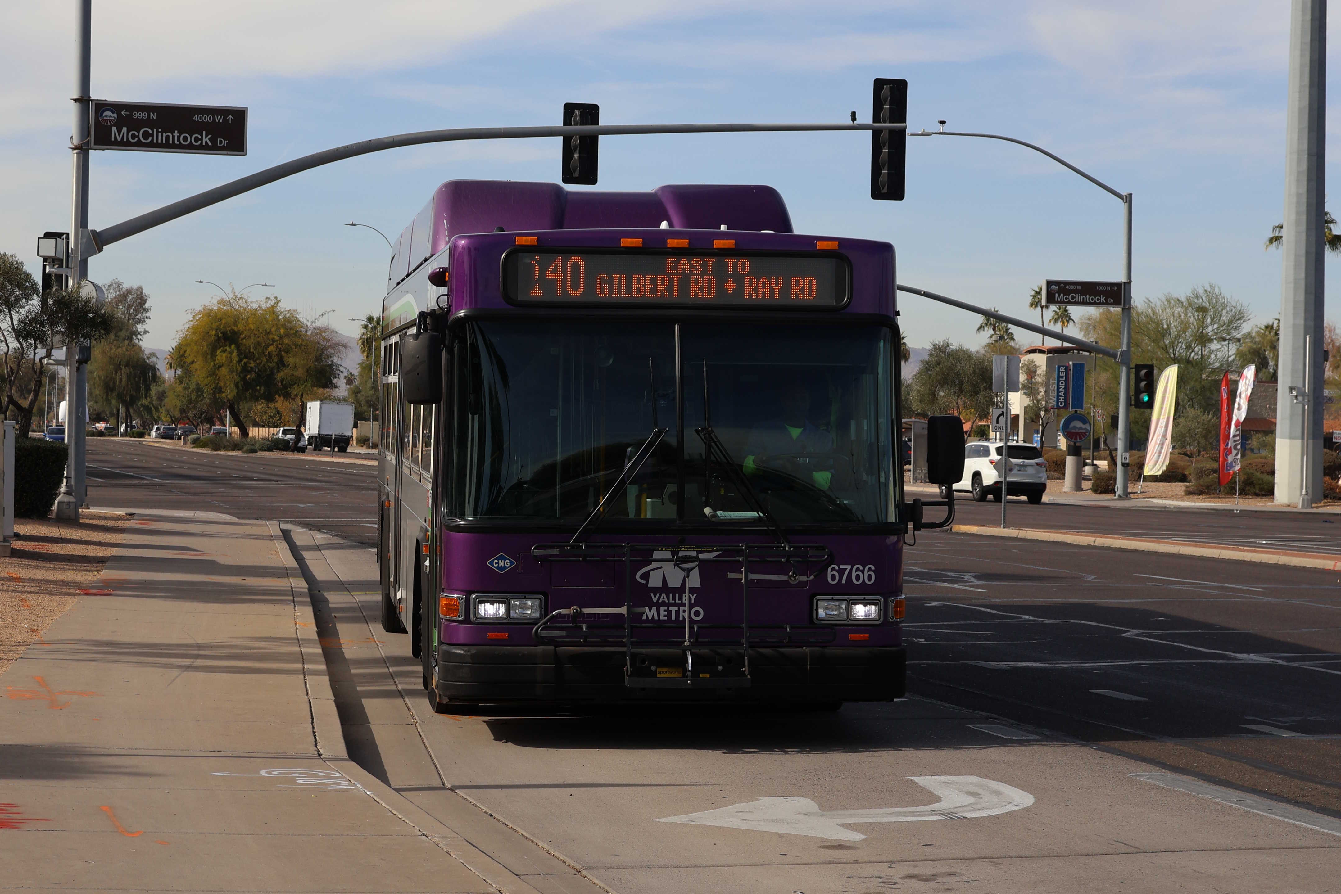 A gray and purple Valley Metro bus, with a white and green stripe, number 6766, traveling eastbound on Ray Road in Chandler on route 140 to Ray Road and Gilbert Road