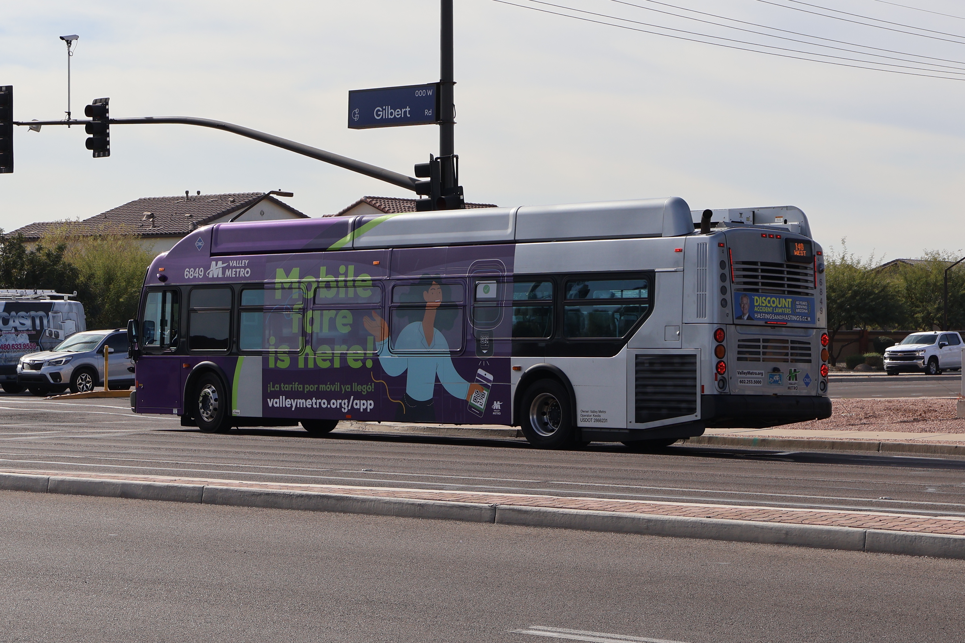 A gray and purple Valley Metro bus, with a green stripe, number 6849, traveling southbound on Gilbert Road in Gilbert on route 140 to Ray Road and 48th Street