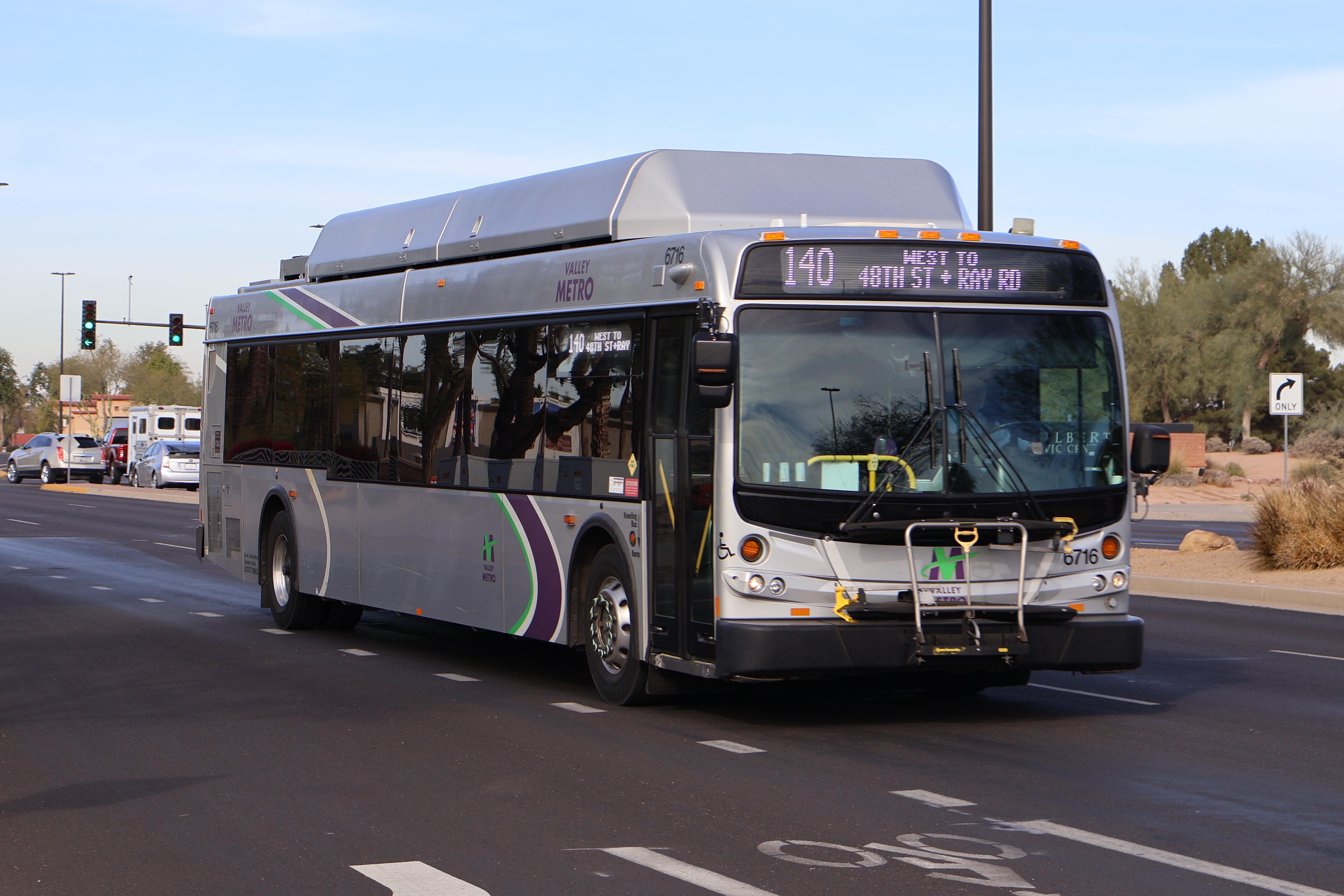 A silver Valley Metro bus, with green, purple, and white stripes, number 6716, traveling southbound on Gilbert Road in Gilbert on route 140 to Ray Road and 48th Street