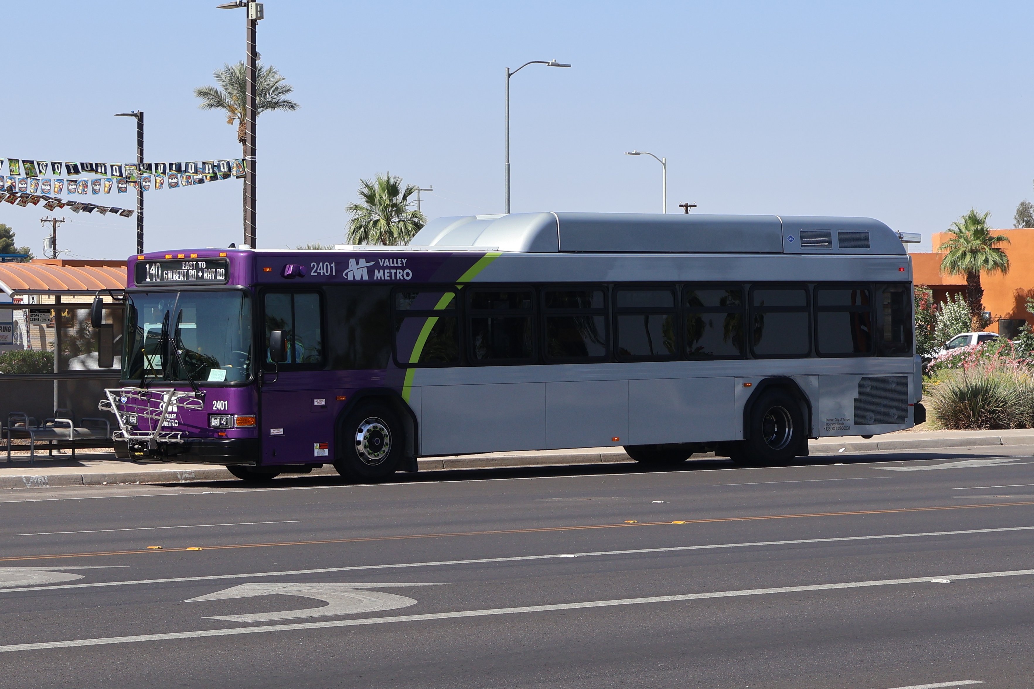 A gray and purple Valley Metro bus, with a green stripe, number 2401, traveling eastbound on Ray Road in Chandler on route 140 to Ray Road and Gilbert Road