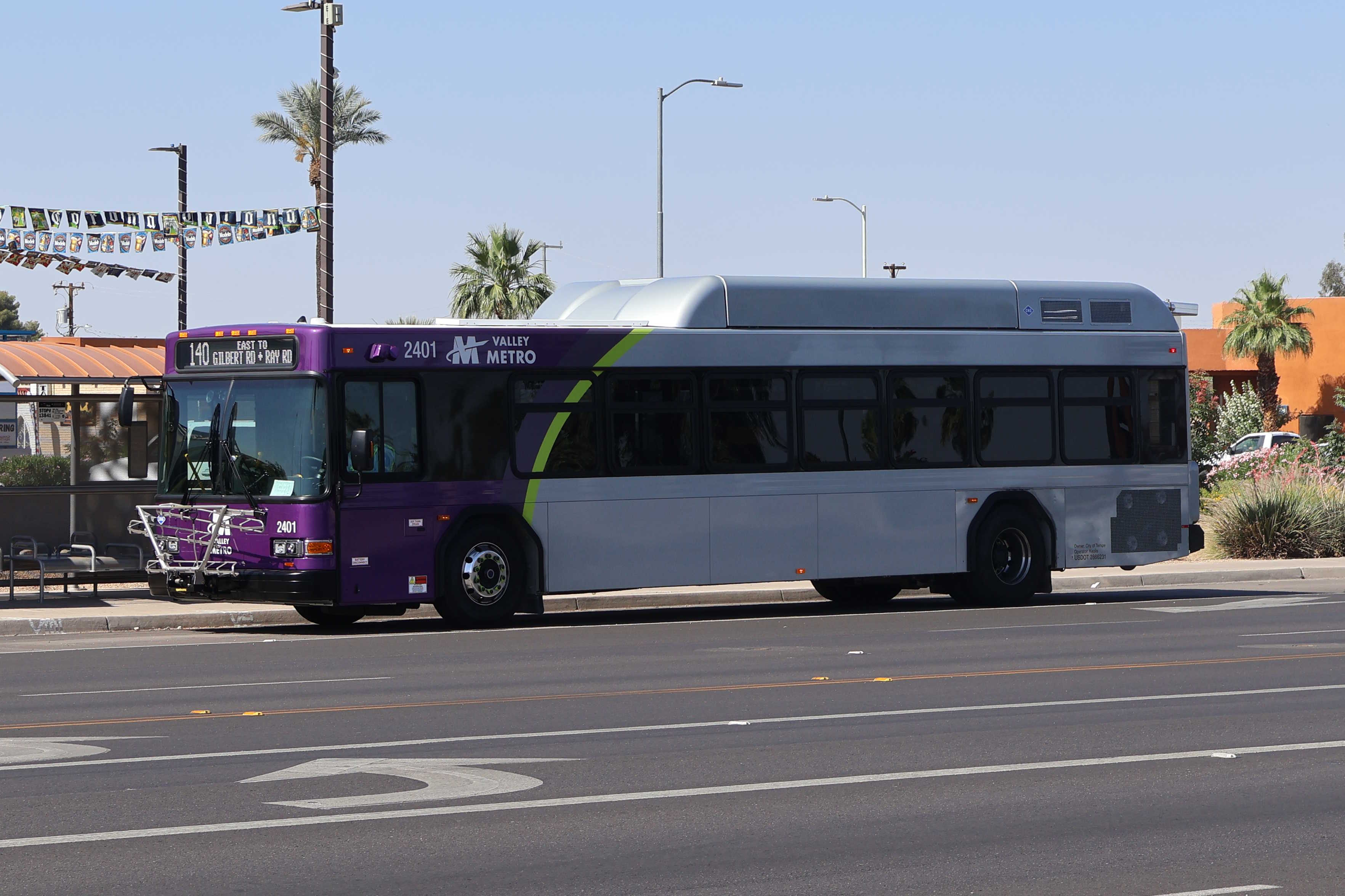 A gray and purple Valley Metro bus, with a green stripe, number 2401, traveling eastbound on Ray Road in Chandler on route 140 to Ray Road and Gilbert Road