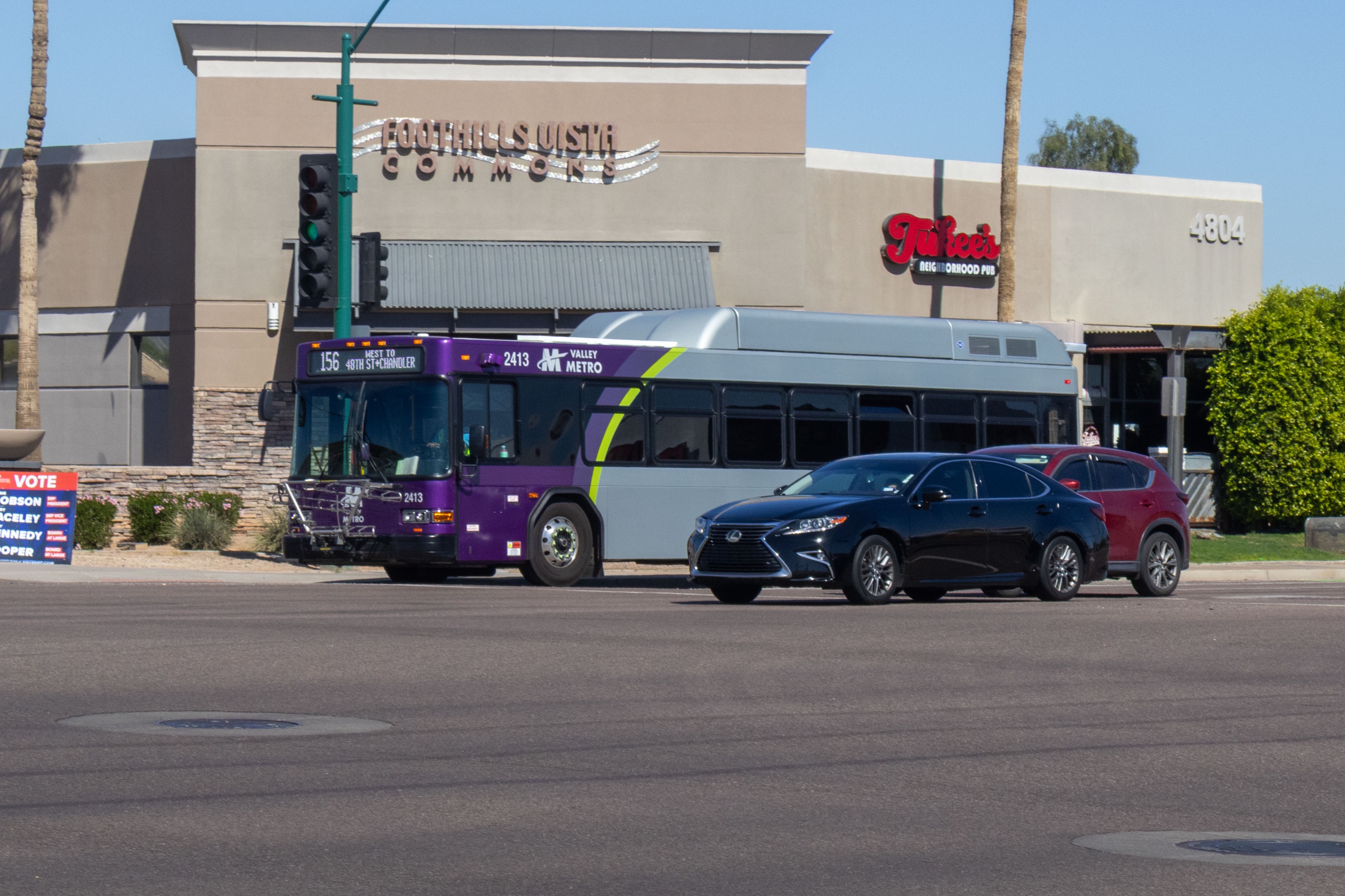 A gray and purple Valley Metro bus, with a green stripe, number 2413, traveling westbound on Chandler Boulevard in Phoenix on route 156 to 48th Street and Chandler Bouelvard
