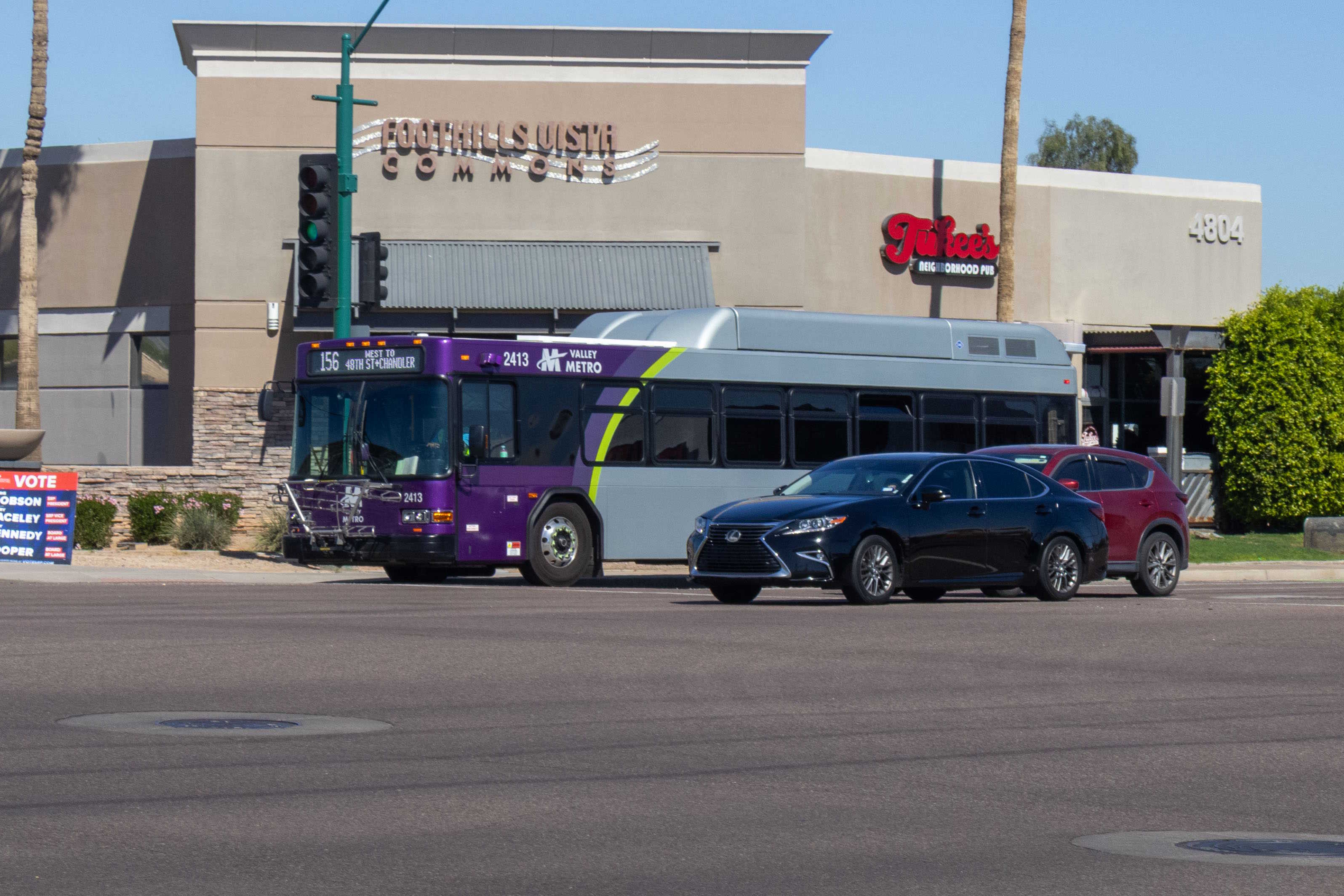 A gray and purple Valley Metro bus, with a green stripe, number 2413, traveling westbound on Chandler Boulevard in Phoenix on route 156 to 48th Street and Chandler Bouelvard
