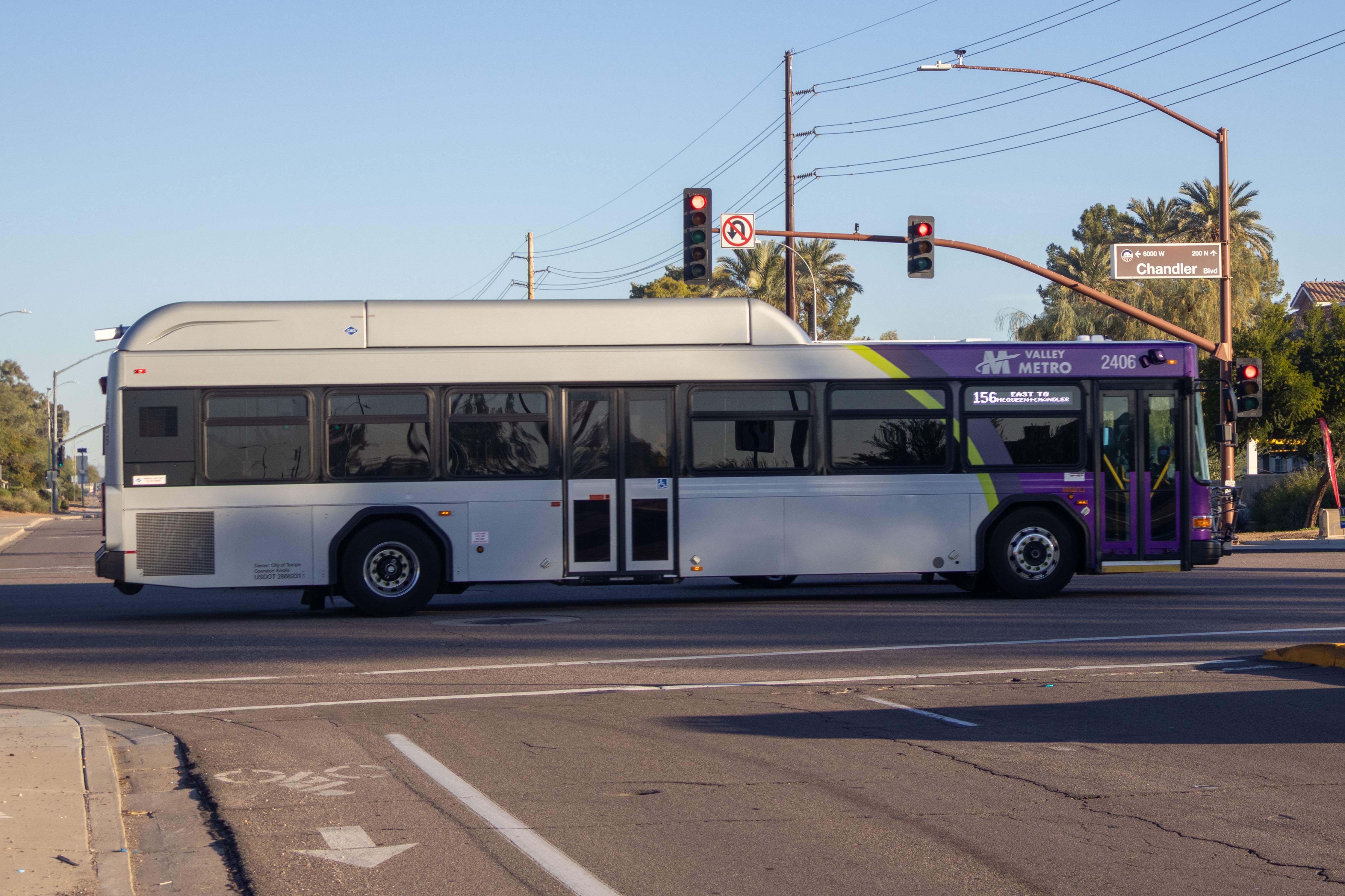 A gray and purple Valley Metro bus, with a green stripe, number 2406, traveling eastbound on Chandler Boulevard in Chandler on route 156 to Chandler Boulevard and McQueen Road