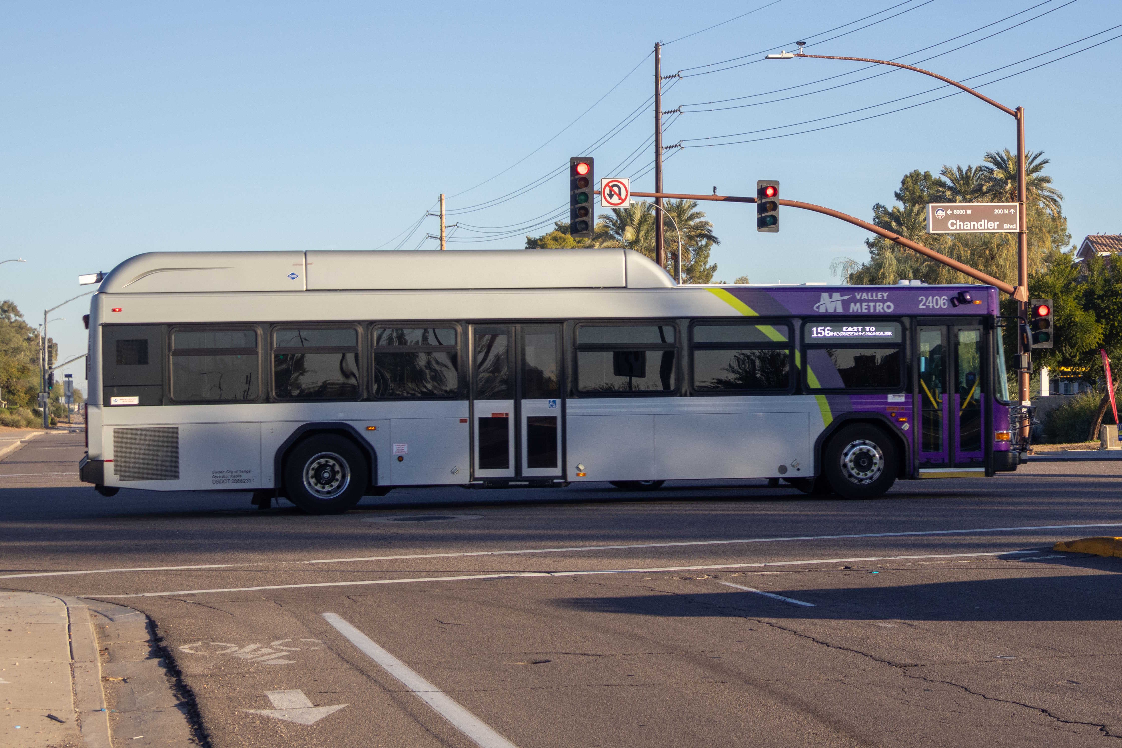 A gray and purple Valley Metro bus, with a green stripe, number 2406, traveling eastbound on Chandler Boulevard in Chandler on route 156 to Chandler Boulevard and McQueen Road
