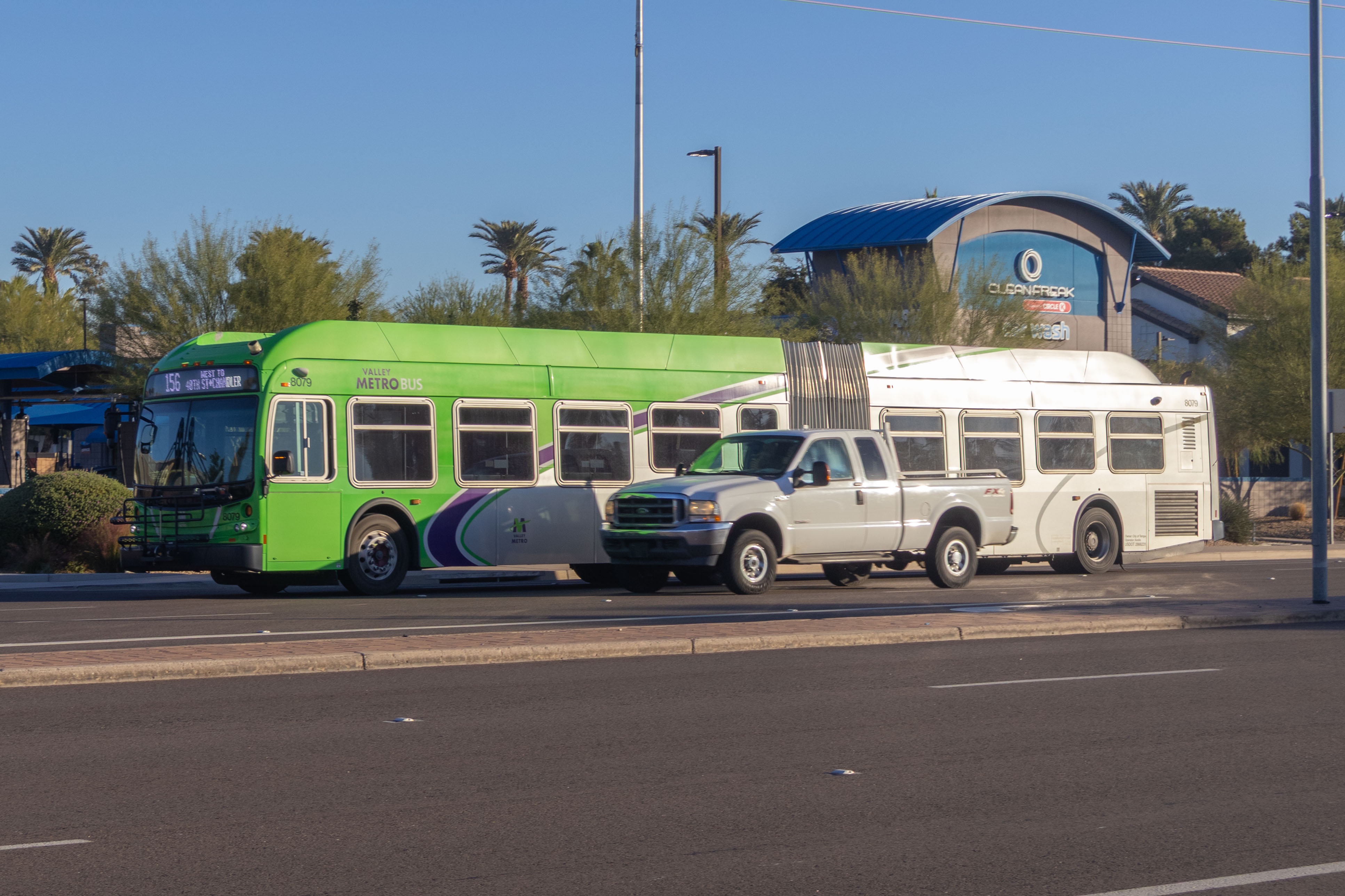 A gray and green articulated Valley Metro bus with a purple and white stripe, number 8079, traveling westbound on Chandler Boulevard in Chandler on route 156 to 48th Street and Chandler Bouelvard