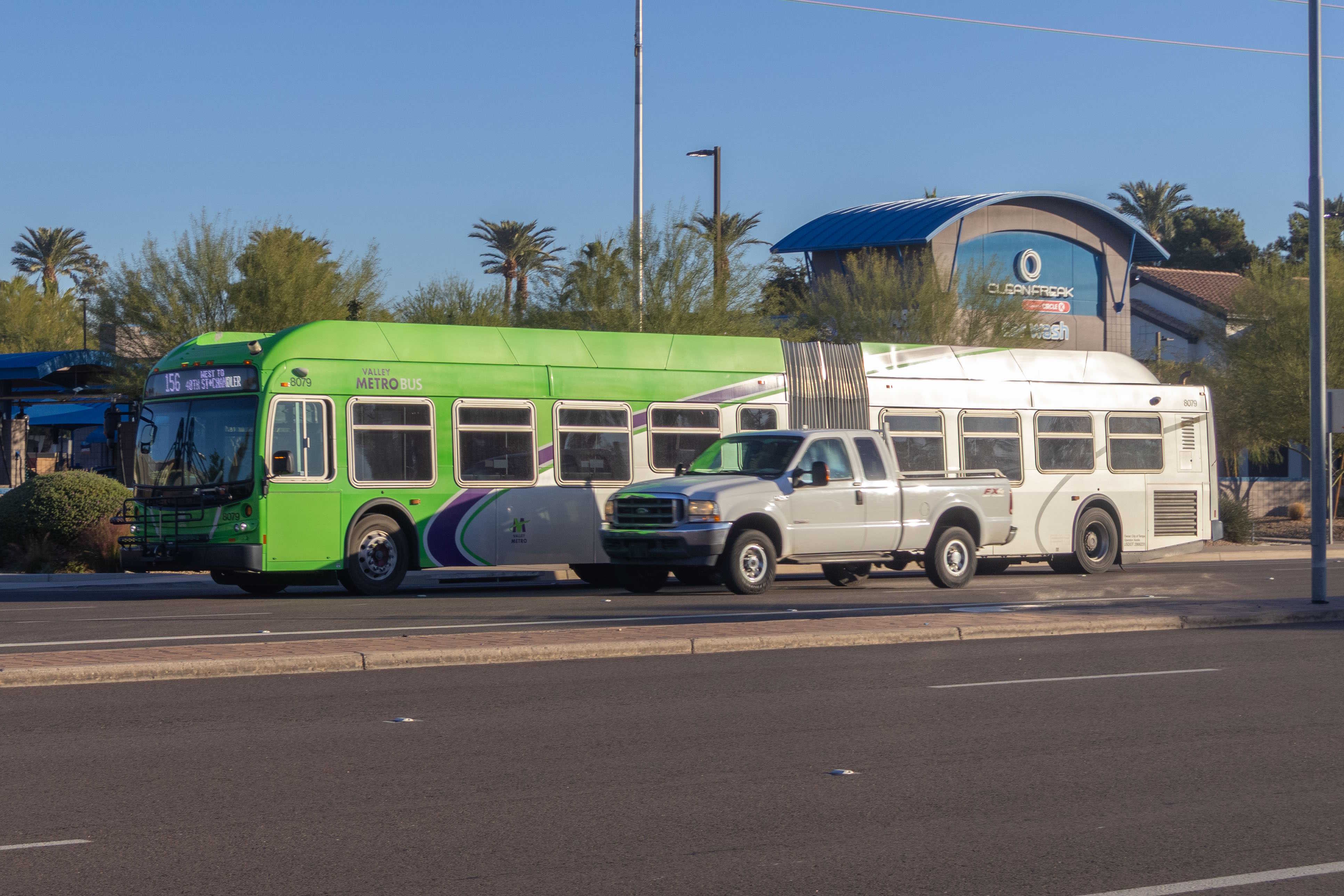 A gray and green articulated Valley Metro bus with a purple and white stripe, number 8079, traveling westbound on Chandler Boulevard in Chandler on route 156 to 48th Street and Chandler Bouelvard