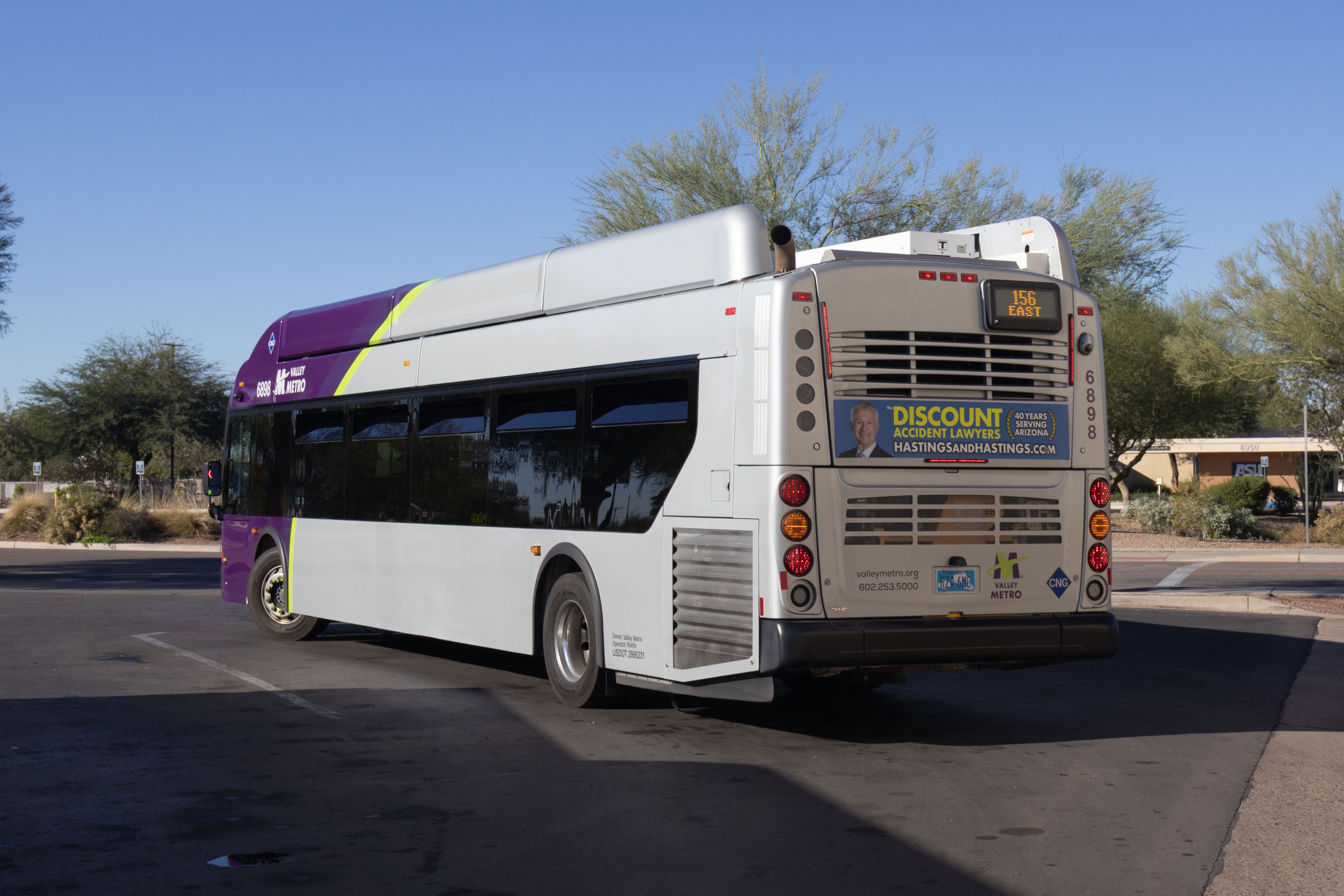 A gray and purple Valley Metro bus, with a green stripe, number 6898, at Tiburon Avenue and Innovation Way in Mesa on route 156 to Arizona State University Polytechnic