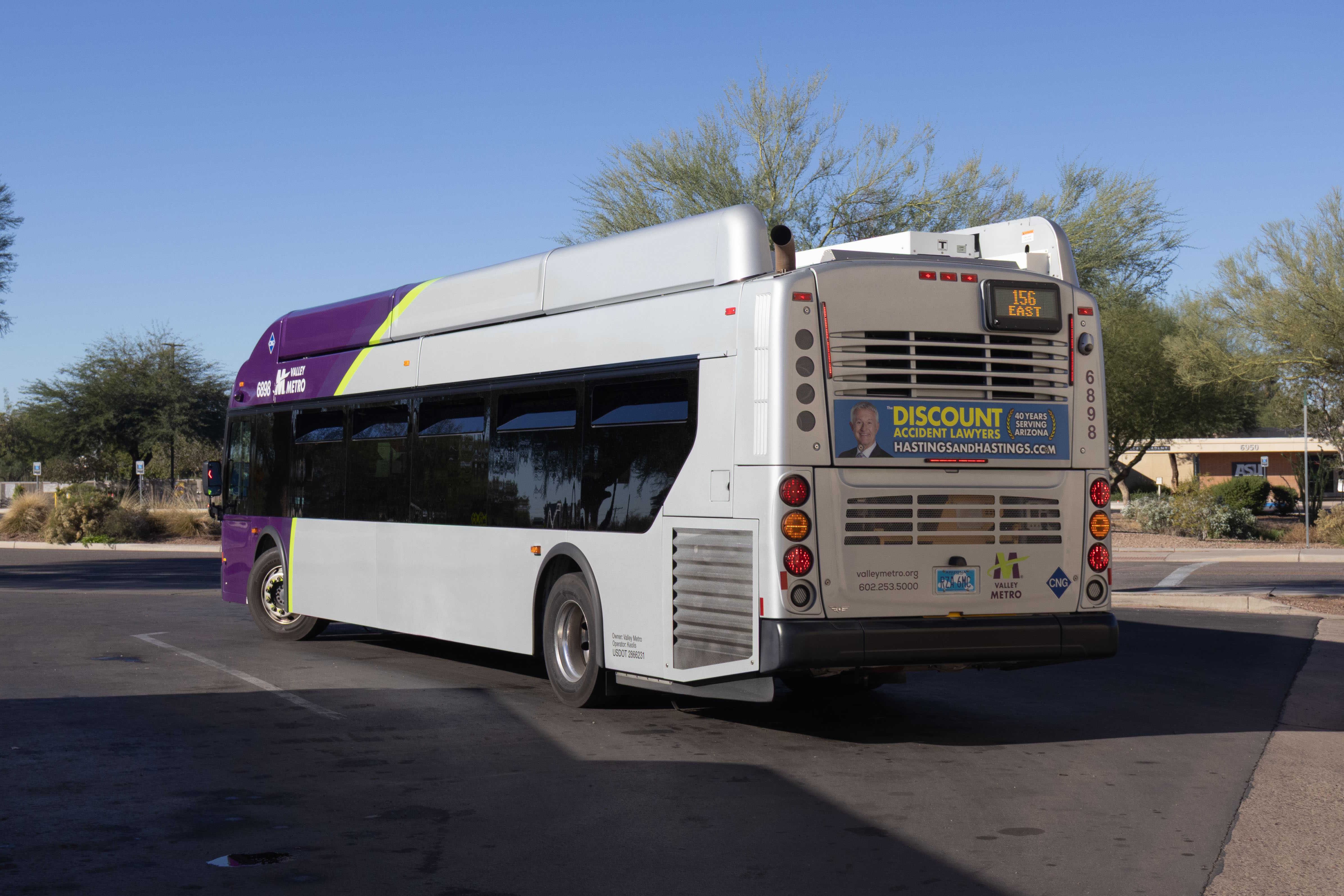 A gray and purple Valley Metro bus, with a green stripe, number 6898, at Tiburon Avenue and Innovation Way in Mesa on route 156 to Arizona State University Polytechnic