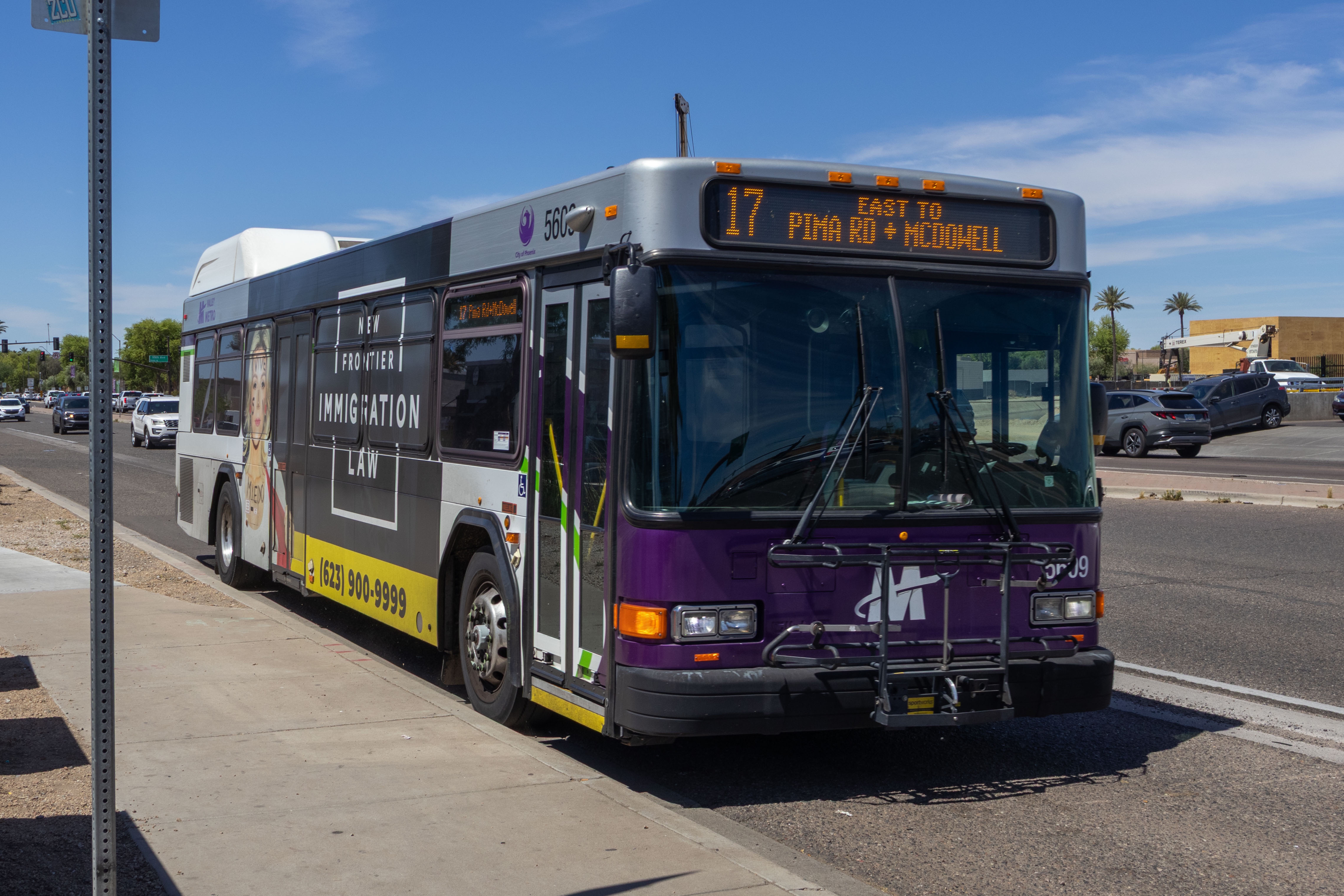 A white and gray Valley Metro bus, with purple and green accent colors, number 5609, traveling eastbound on McDowell Road in Tolleson on route 17 to McDowell Road and Pima Road
