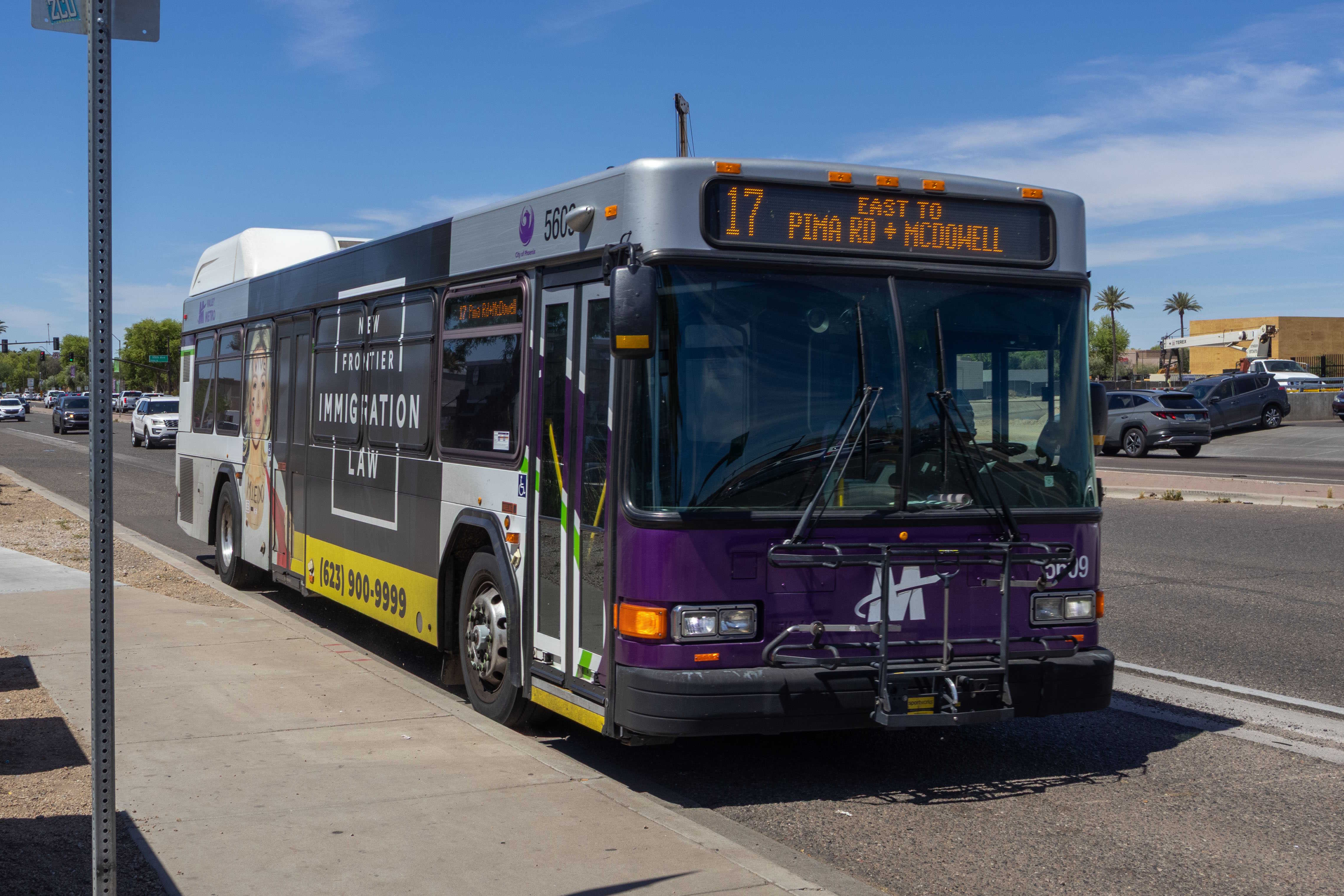 A white and gray Valley Metro bus, with purple and green accent colors, number 5609, traveling eastbound on McDowell Road in Tolleson on route 17 to McDowell Road and Pima Road