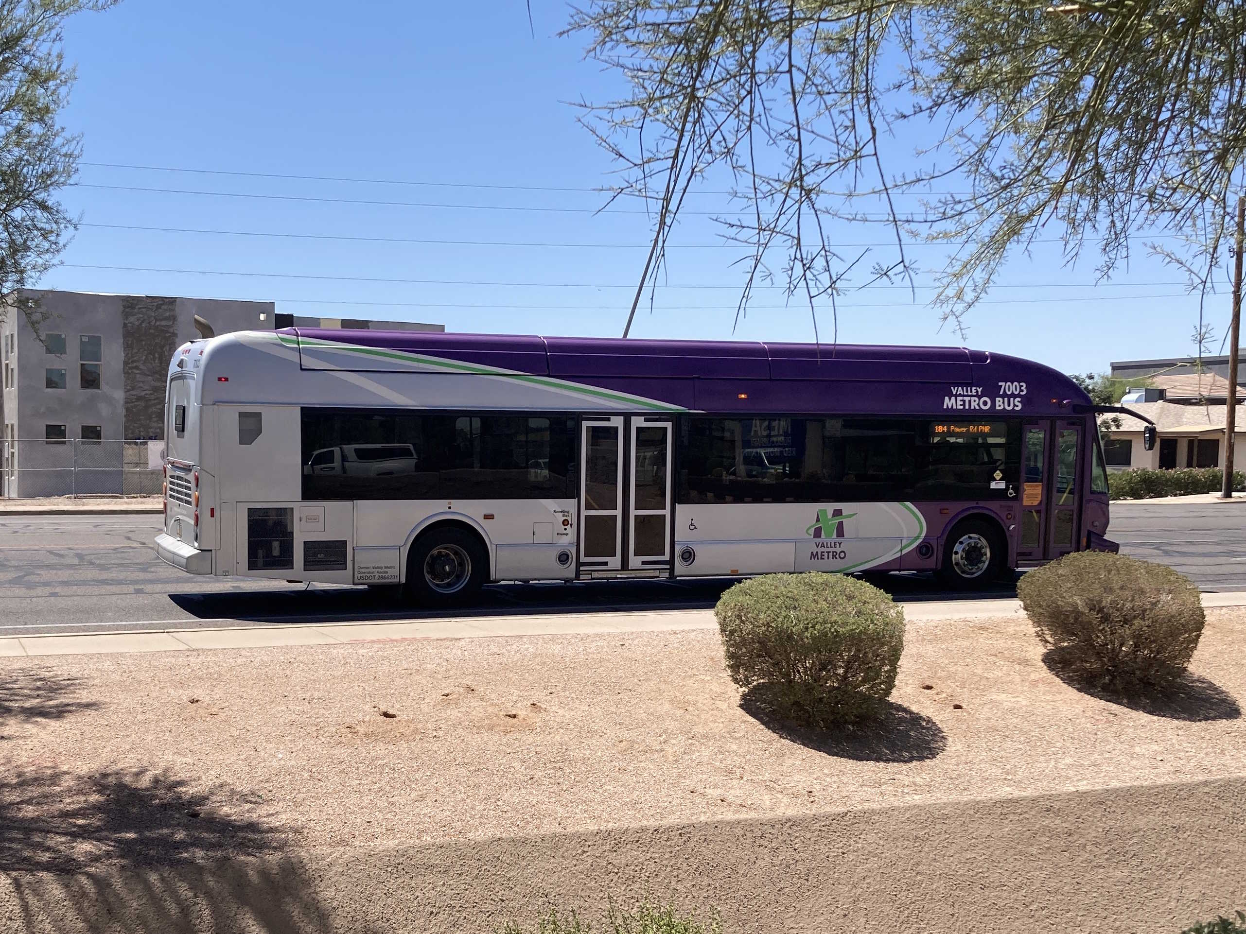 A purple and gray Valley Metro bus, with green and white stripes, number 7003, traveling northbound on Power Road in Mesa on route 184 to Power Road Park and Ride