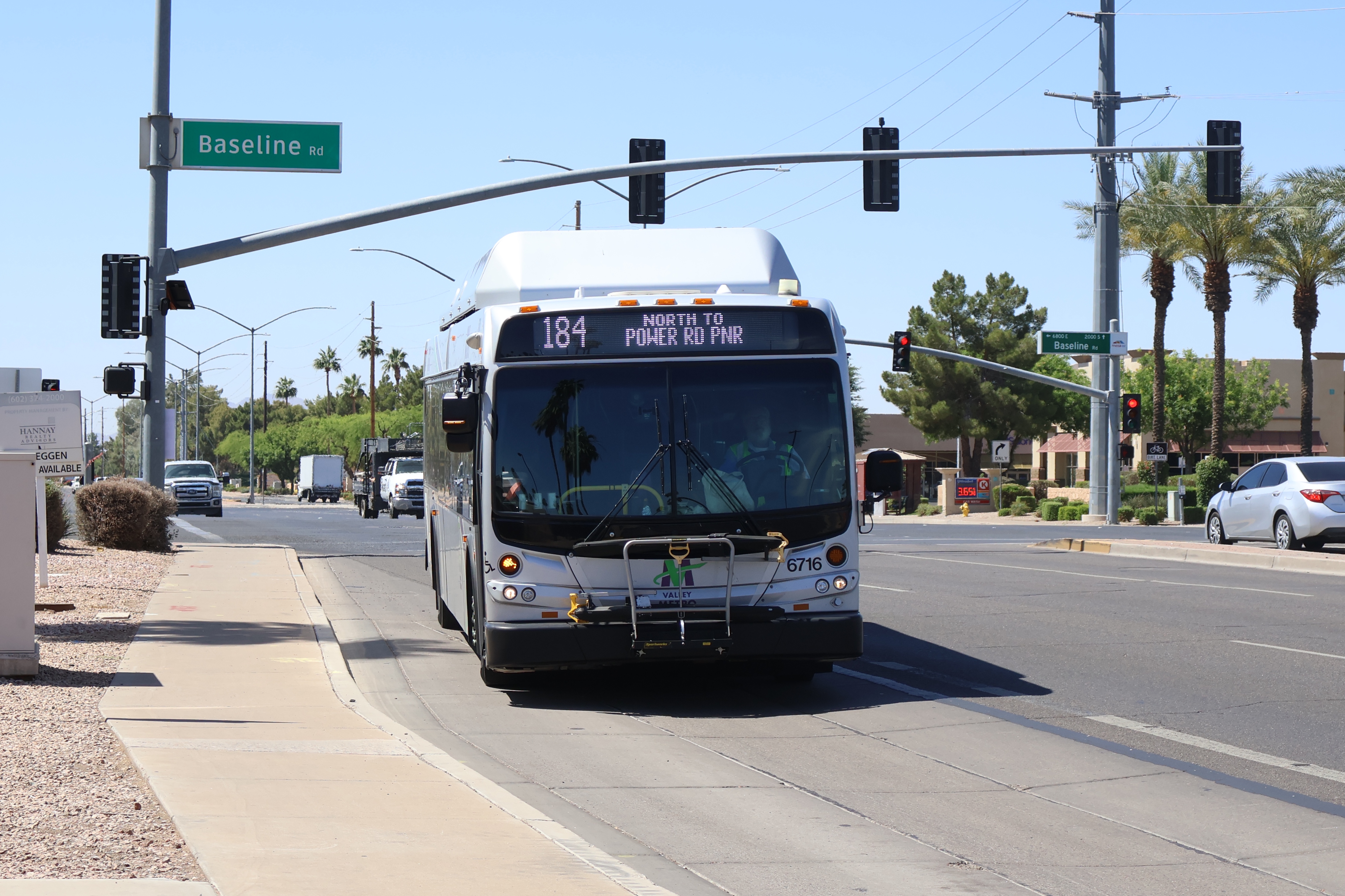 A silver Valley Metro bus, with green, purple, and white stripes, number 6716, traveling northbound on Power Road in Mesa on route 184 to Power Road Park and Ride