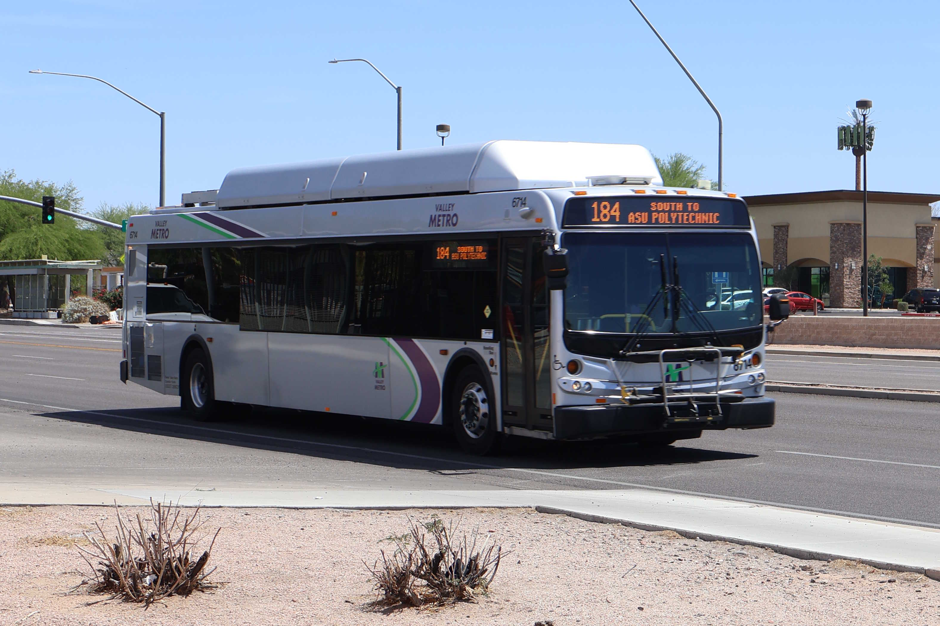 A silver Valley Metro bus, with green, purple, and white stripes, number 6714, traveling southbound on Power Road in Mesa on route 184 to Arizona State University Polytechnic
