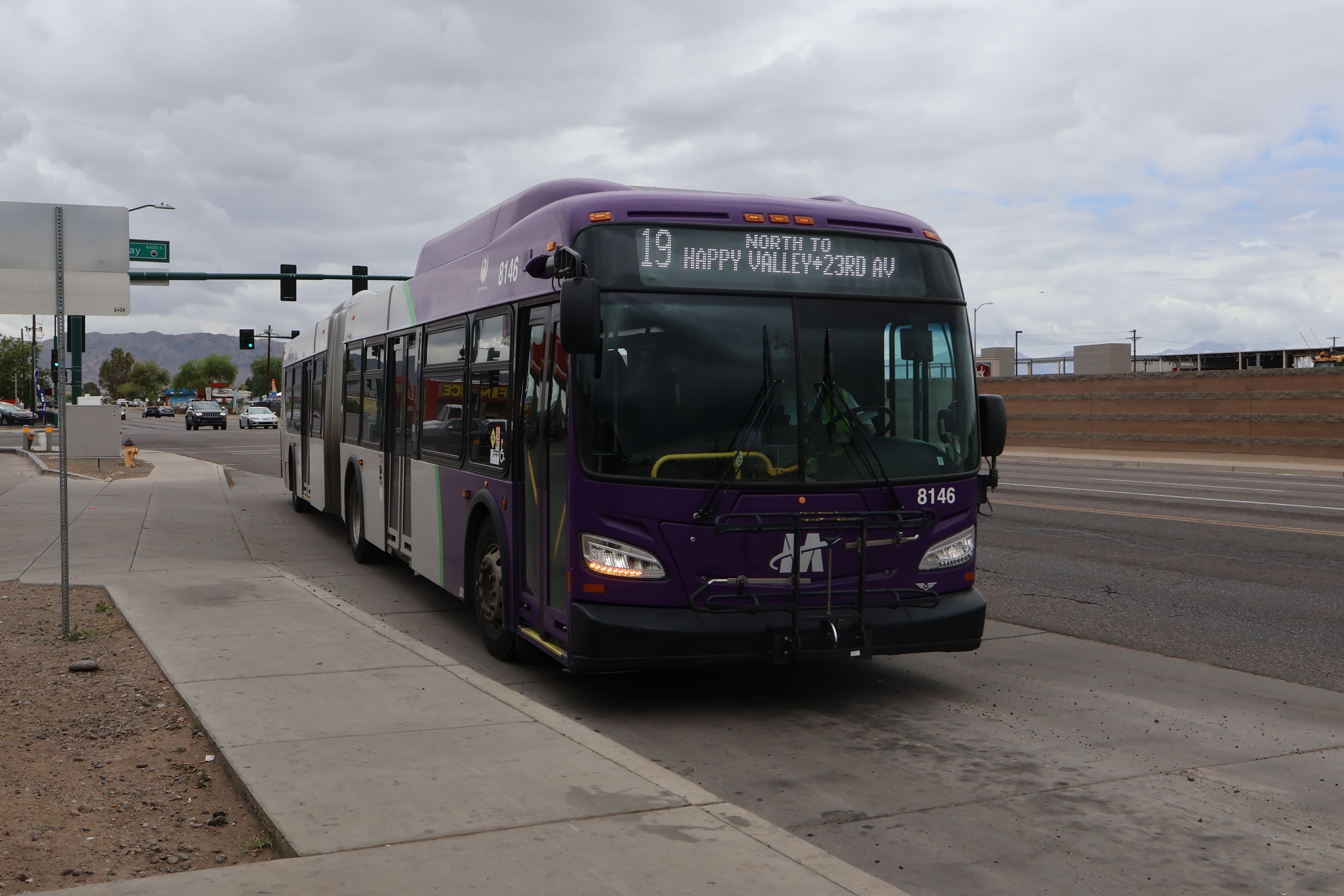 A purple and gray articulated Valley Metro bus, number 8146, traveling northbound on 19th Avenue in Phoenix on route 19 to 23rd Avenue and Happy Valley Road