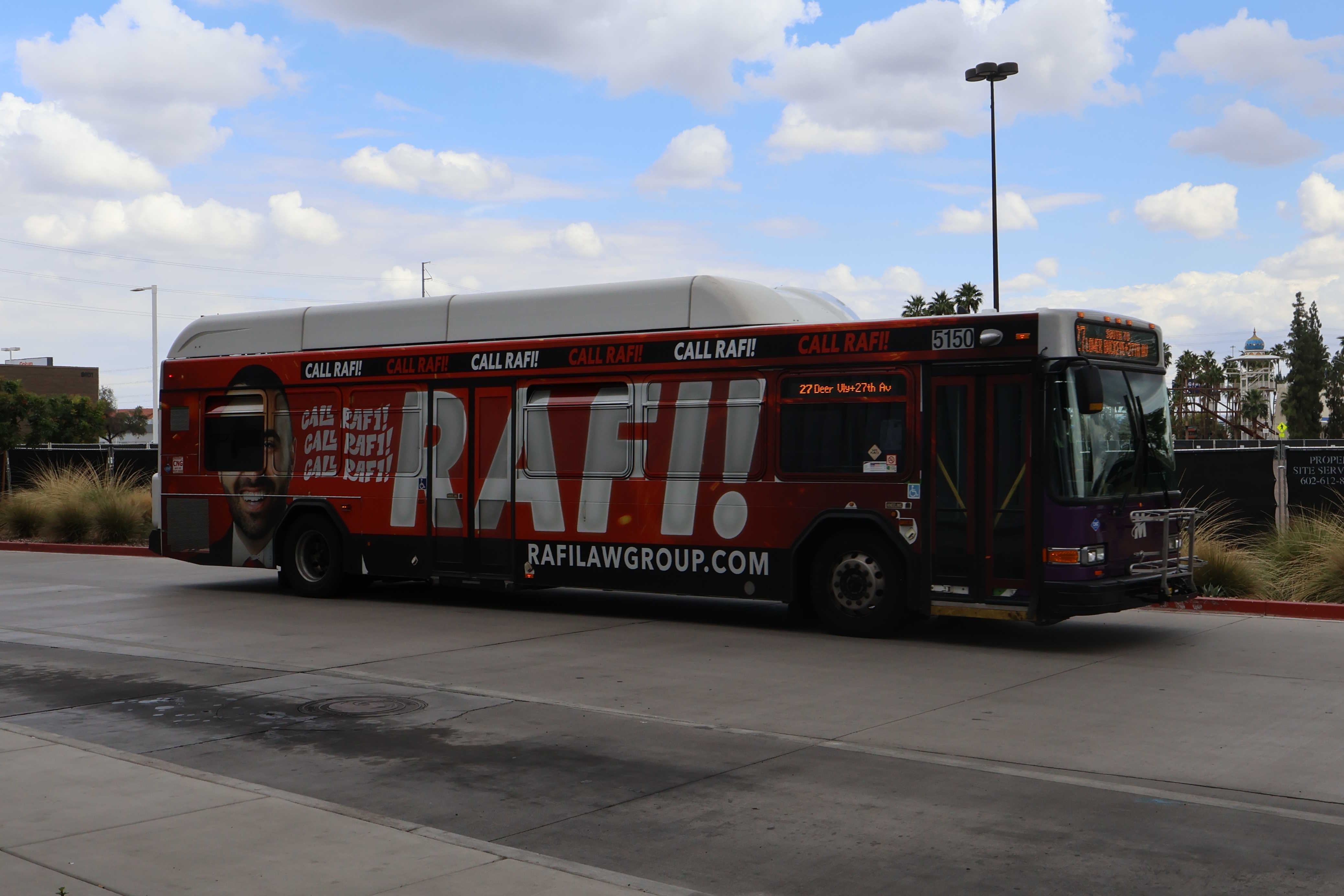 A white and gray Valley Metro bus, with purple and green accent colors, number 5150, at Thelda Williams Transit Center in Phoenix on route 27 to 27th Avenue and Lower Buckeye Road