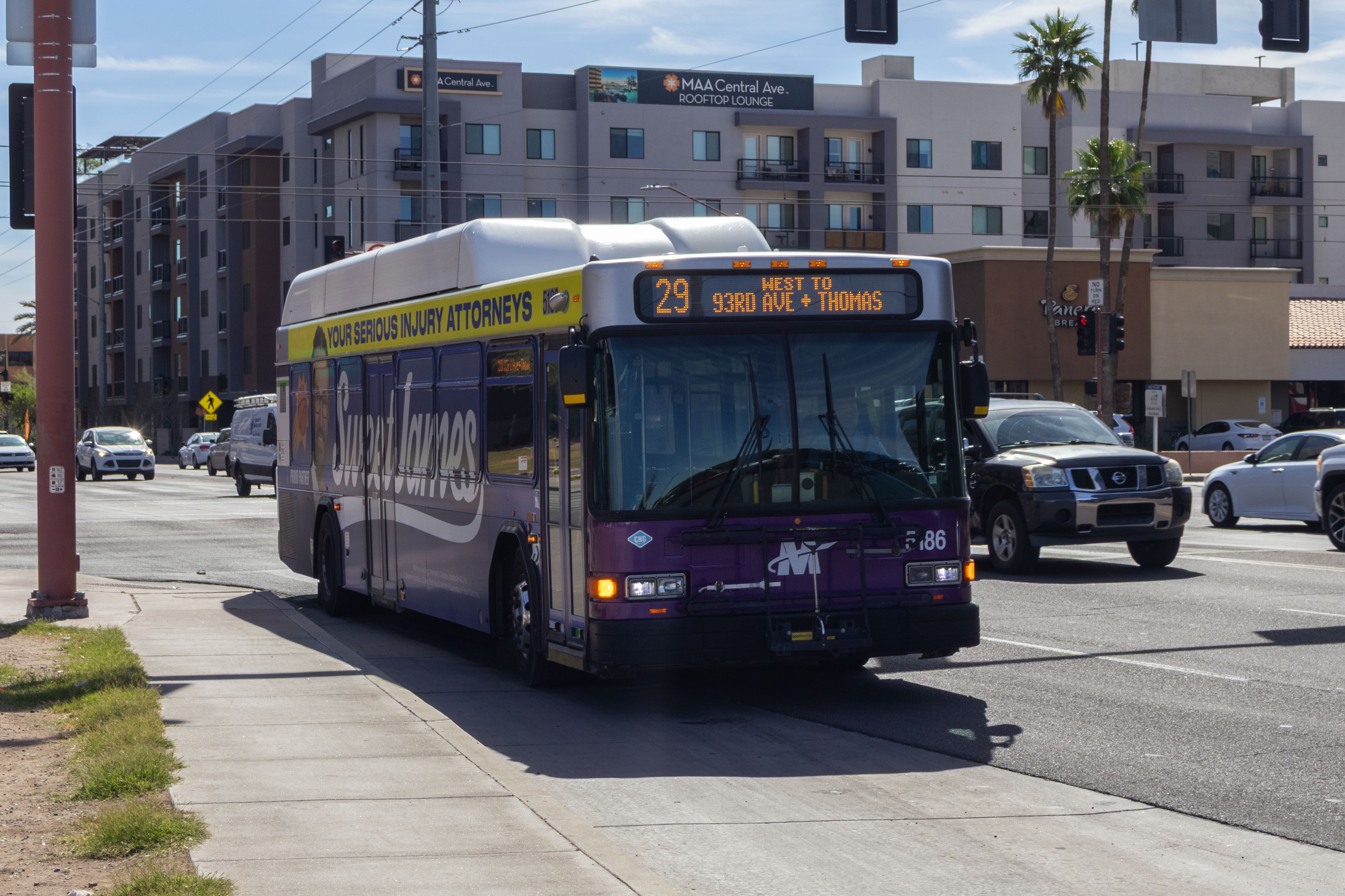 A white and gray Valley Metro bus, with purple and green accent colors, number 5186, traveling westbound on Thomas Road in Phoenix on route 29 to Thomas Road and 93rd Avenue