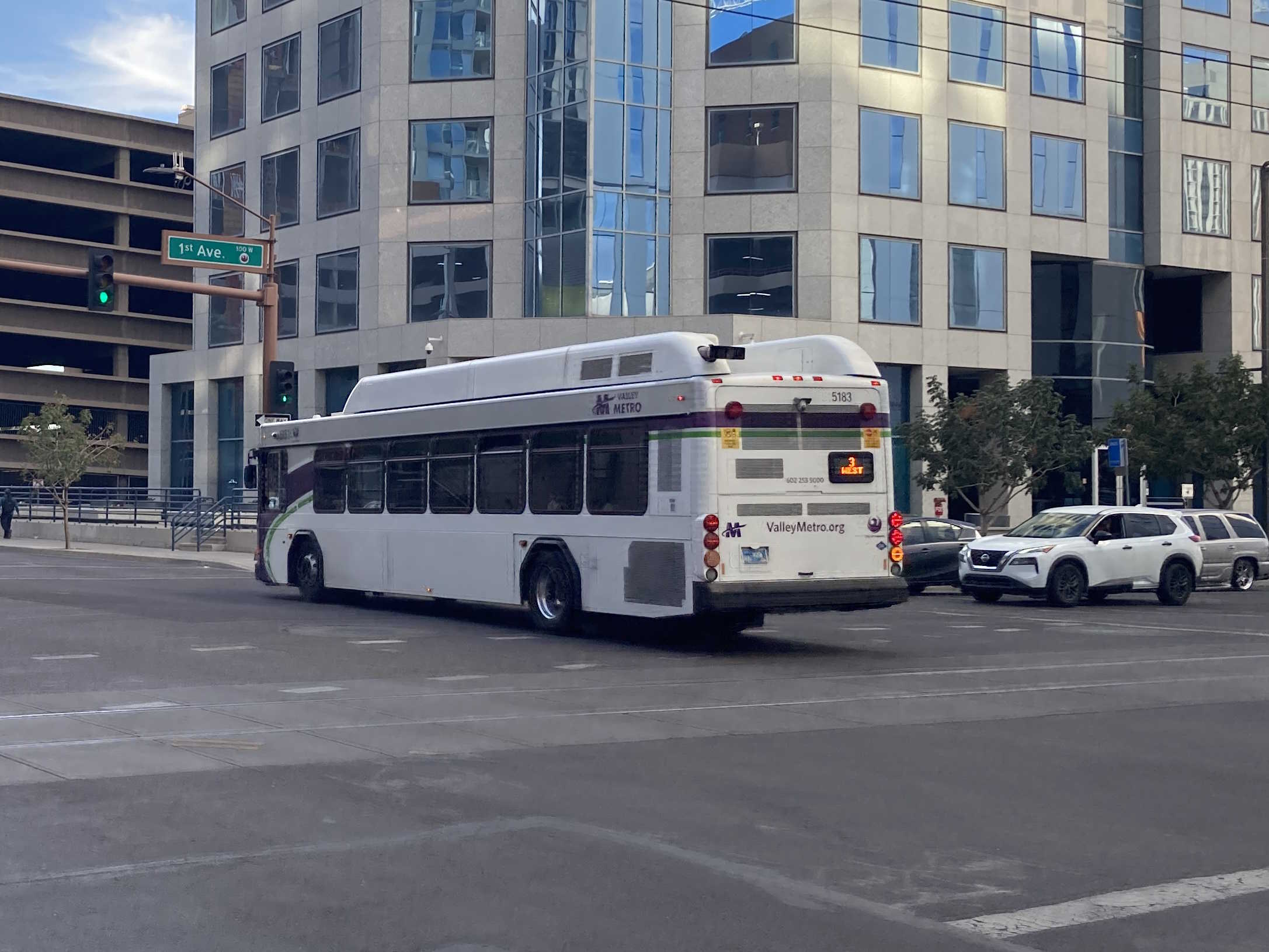 A white and gray Valley Metro bus, with purple and green accent colors, number 5183, traveling westbound on Van Buren Street in Phoenix on route 3 to 4th Street and La Canada Boulevard