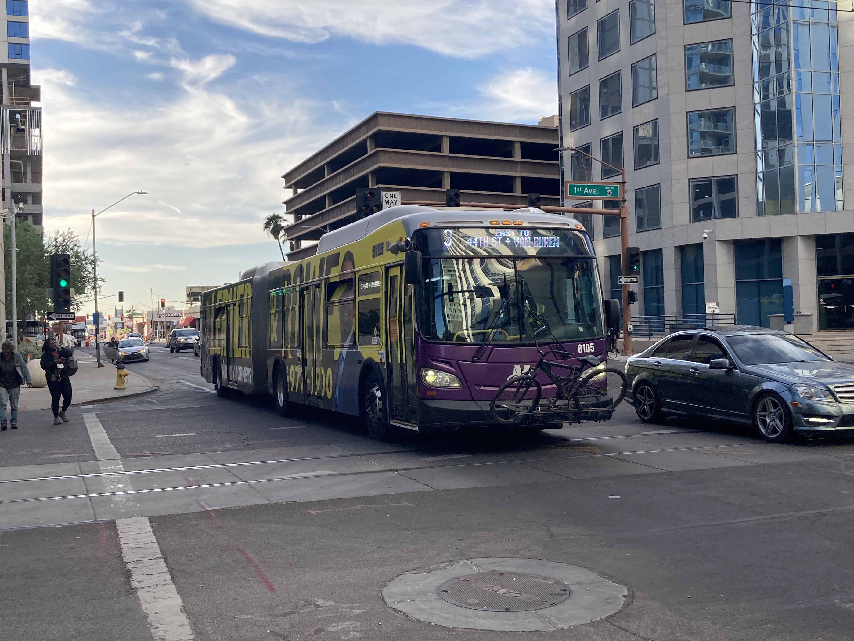 A white and gray articulated Valley Metro bus, with purple and green accent colors, number 8105, traveling eastbound on Van Buren Street in Phoenix on route 3 to Van Buren Street and 44th Street