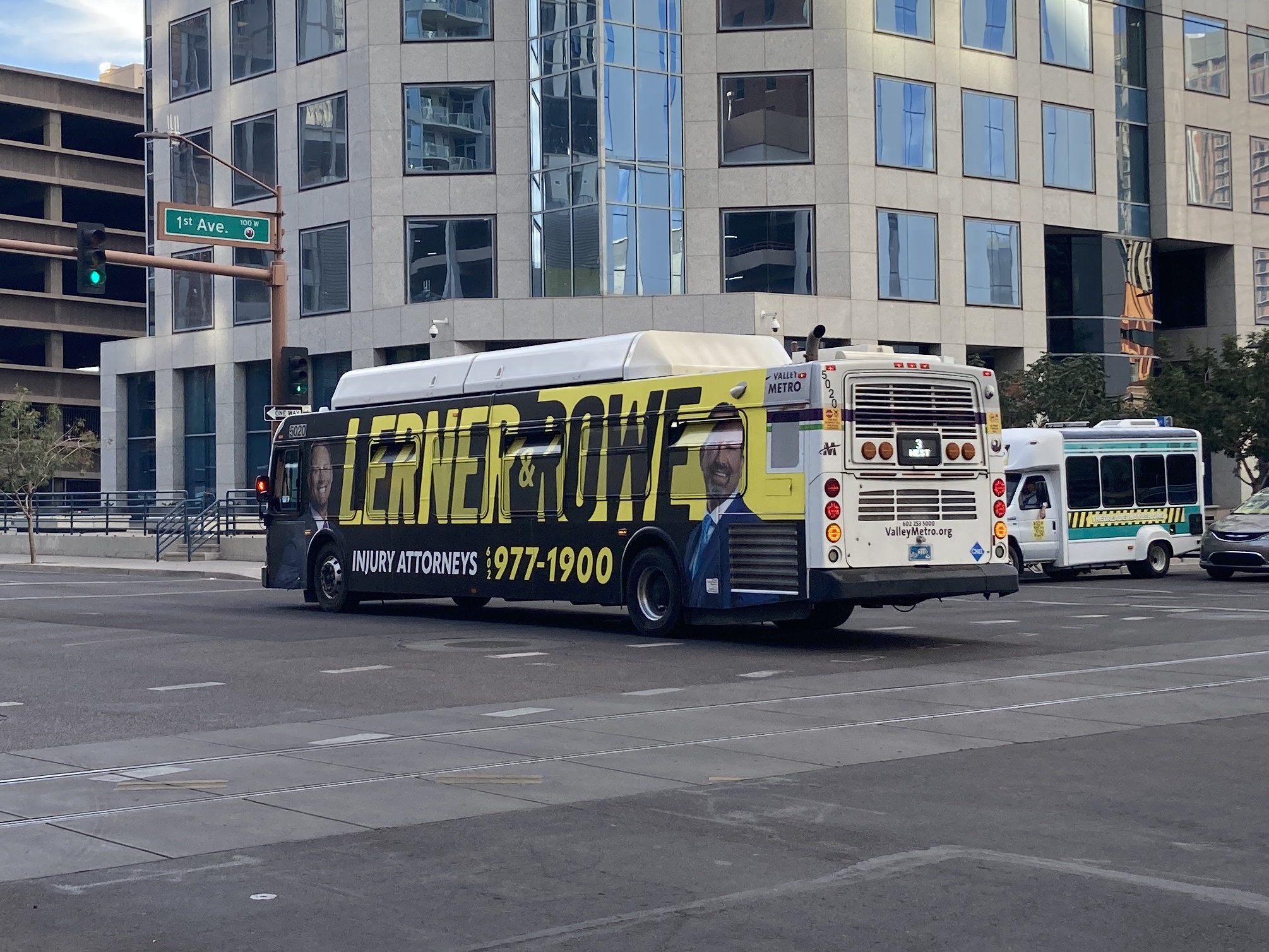 A white and gray Valley Metro bus, with purple and green accent colors, number 5020, traveling westbound on Van Buren Street in Phoenix on route 3 to Van Buren Street and 35th Avenue