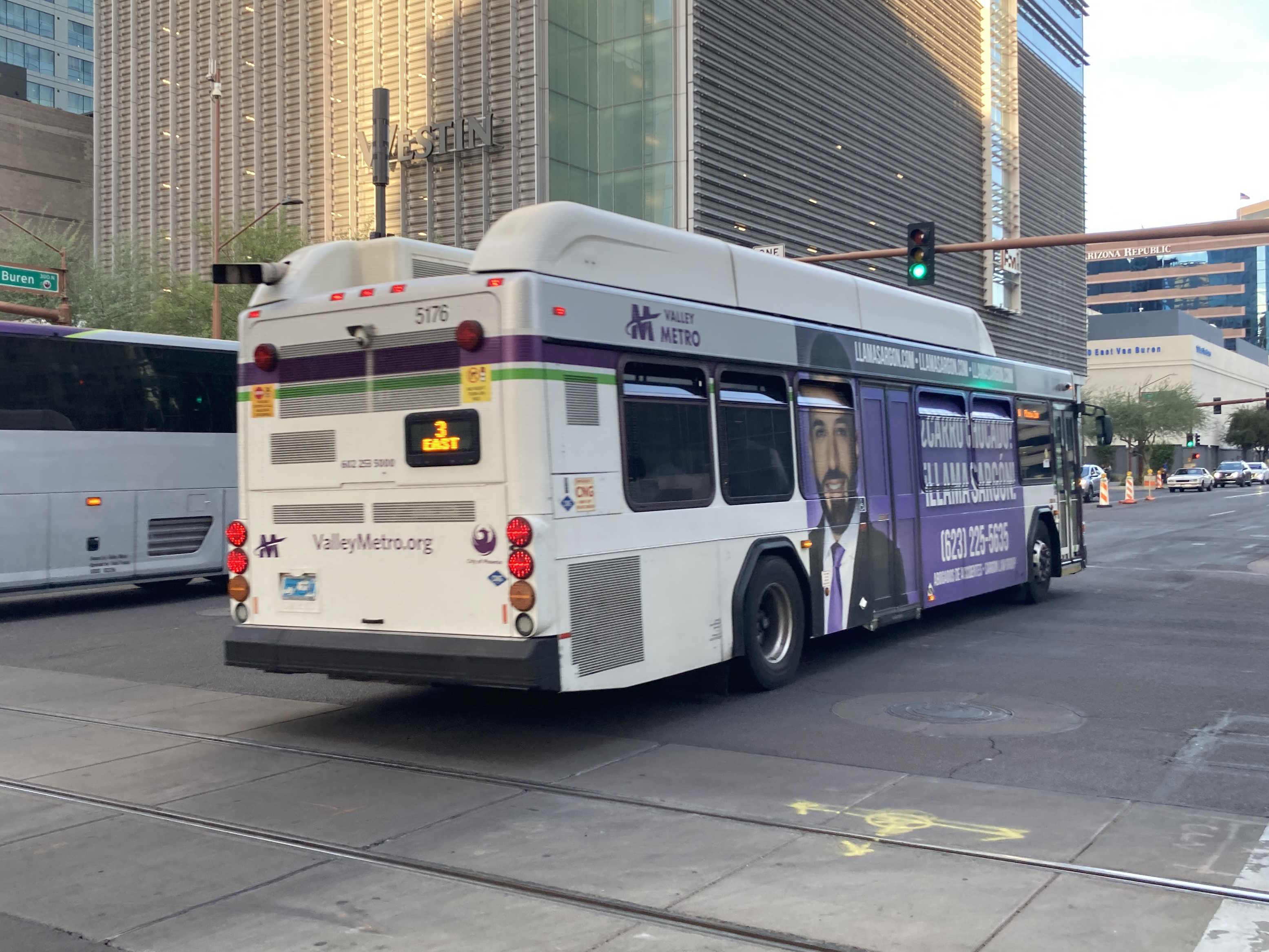 A white and gray Valley Metro bus, with purple and green accent colors, number 5176, traveling eastbound on Van Buren Street in Phoenix on route 3 to the Phoenix Zoo