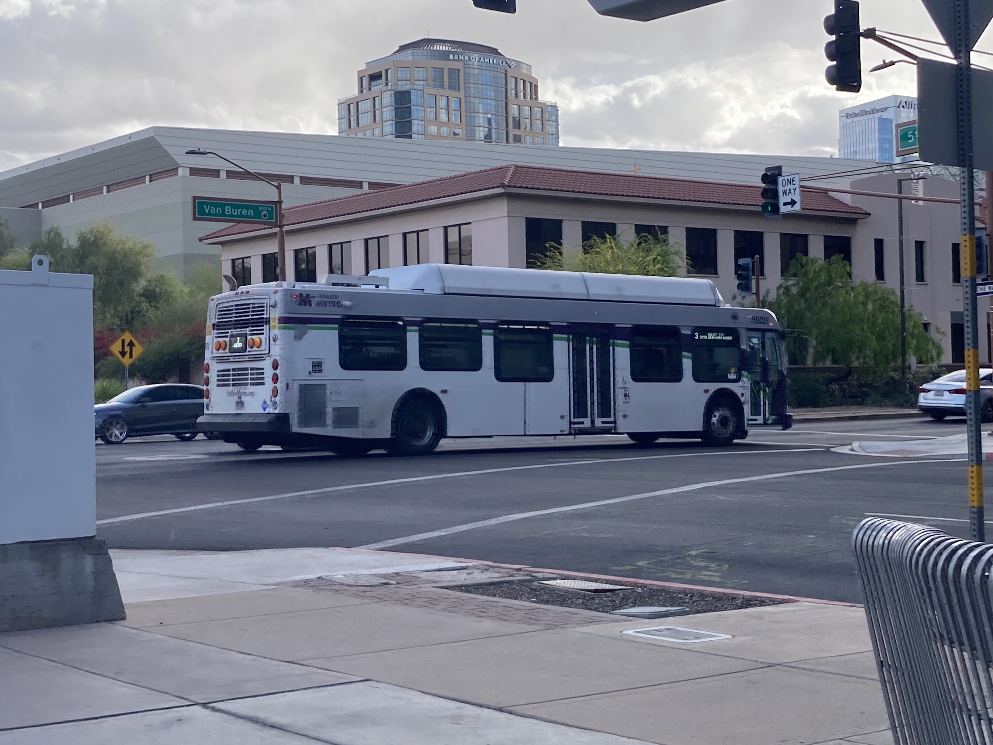 A white and gray Valley Metro bus, with purple and green accent colors, number 5028, traveling westbound on Van Buren Street in Phoenix on route 3 to Van Buren Street and 35th Avenue