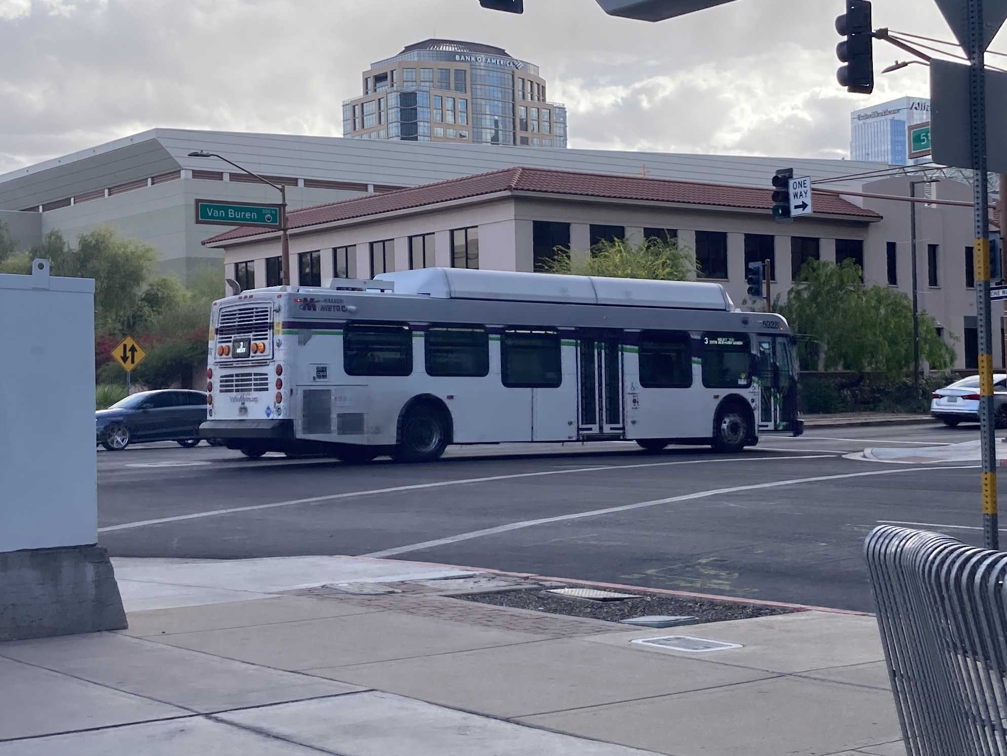 A white and gray Valley Metro bus, with purple and green accent colors, number 5028, traveling westbound on Van Buren Street in Phoenix on route 3 to Van Buren Street and 35th Avenue