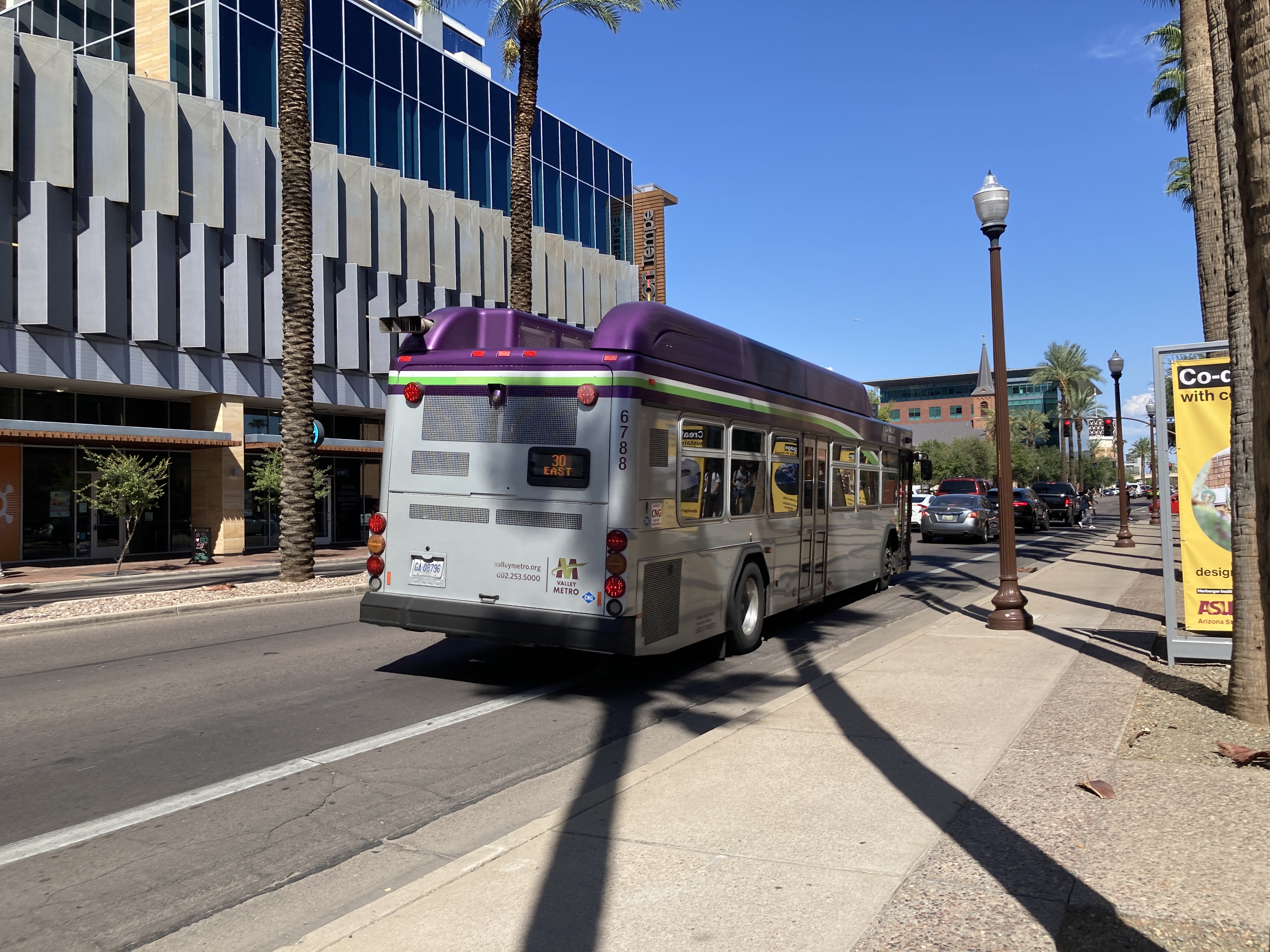 A gray and purple Valley Metro bus, with a white and green stripe, number 6788, traveling eastbound on University Drive in Tempe on route 30 to Power Road & University Drive