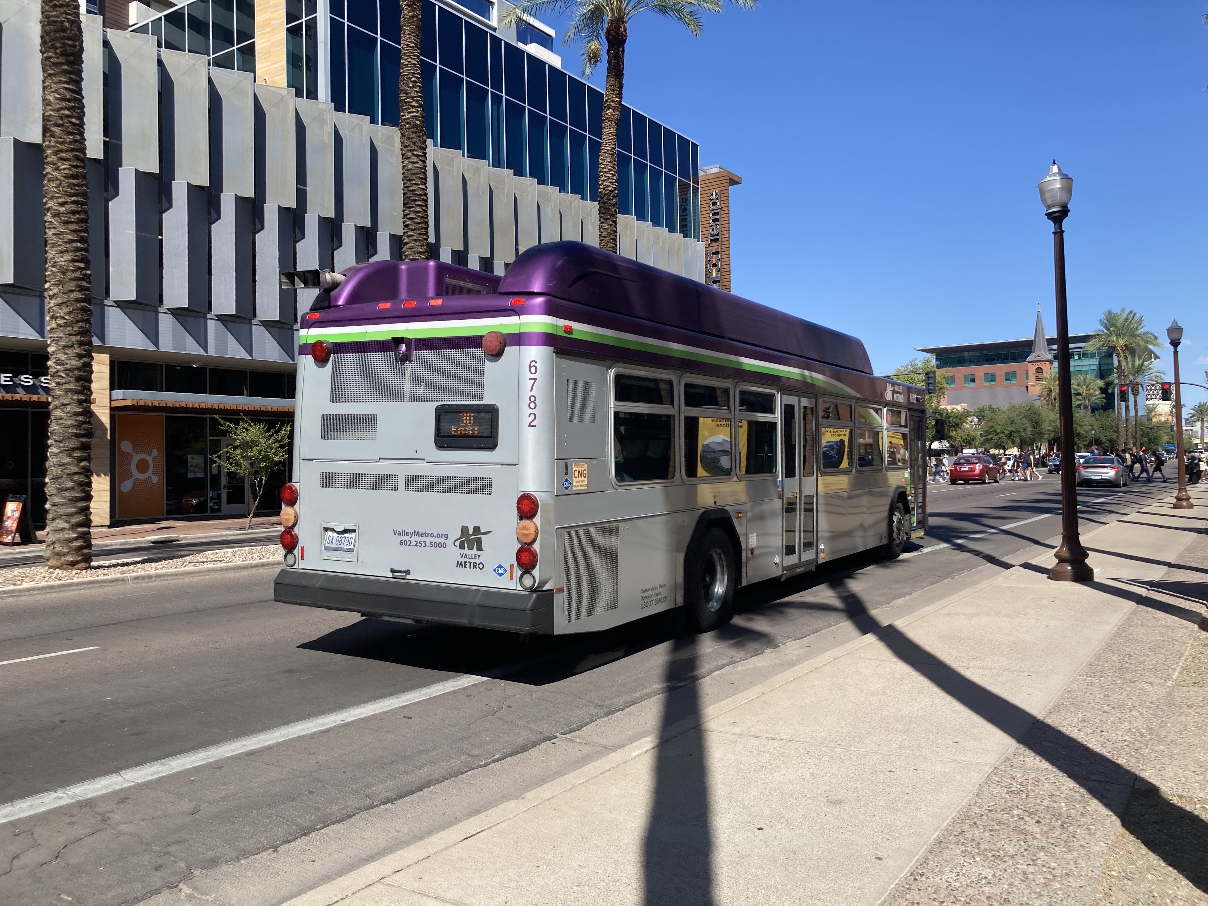 A gray and purple Valley Metro bus, with a white and green stripe, number 6782, traveling eastbound on University Drive in Tempe on route 30 to Power Road & University Drive