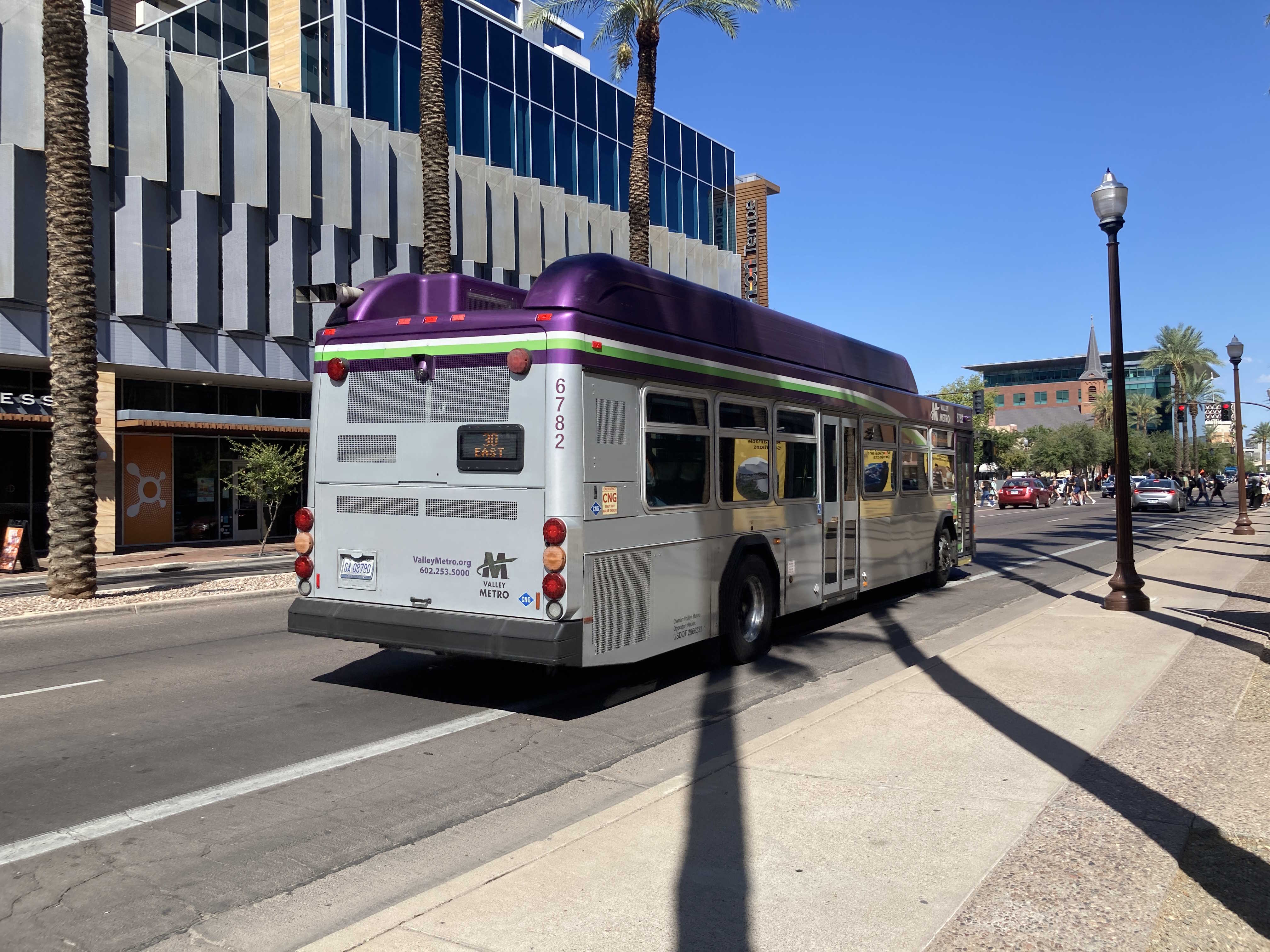 A gray and purple Valley Metro bus, with a white and green stripe, number 6782, traveling eastbound on University Drive in Tempe on route 30 to Power Road and University Drive