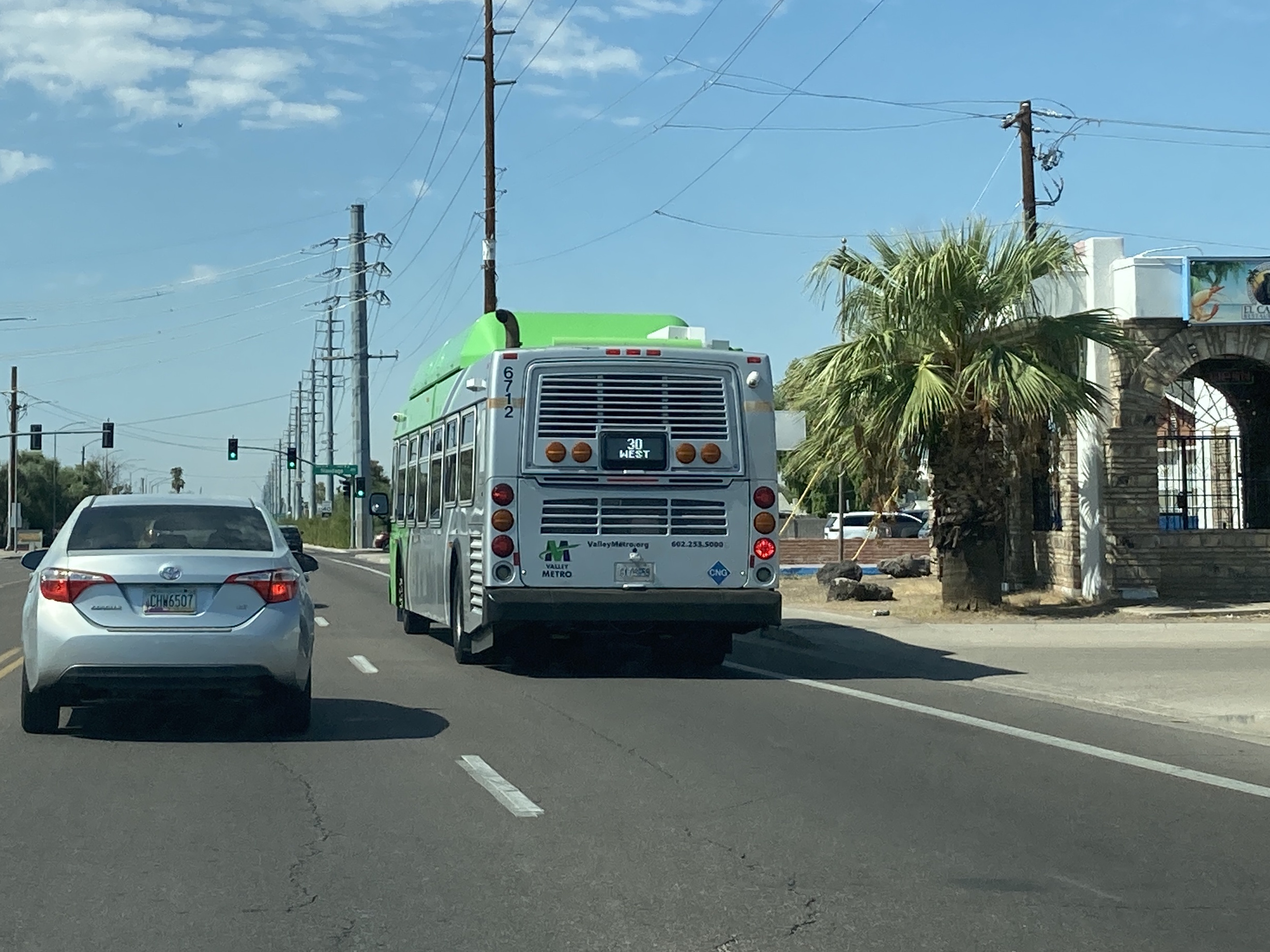 A green and gray Valley Metro bus, with a purple stripe, number 6712, traveling westbound on University Drive in Mesa on route 30 to 24th Street/Baseline Park and Ride