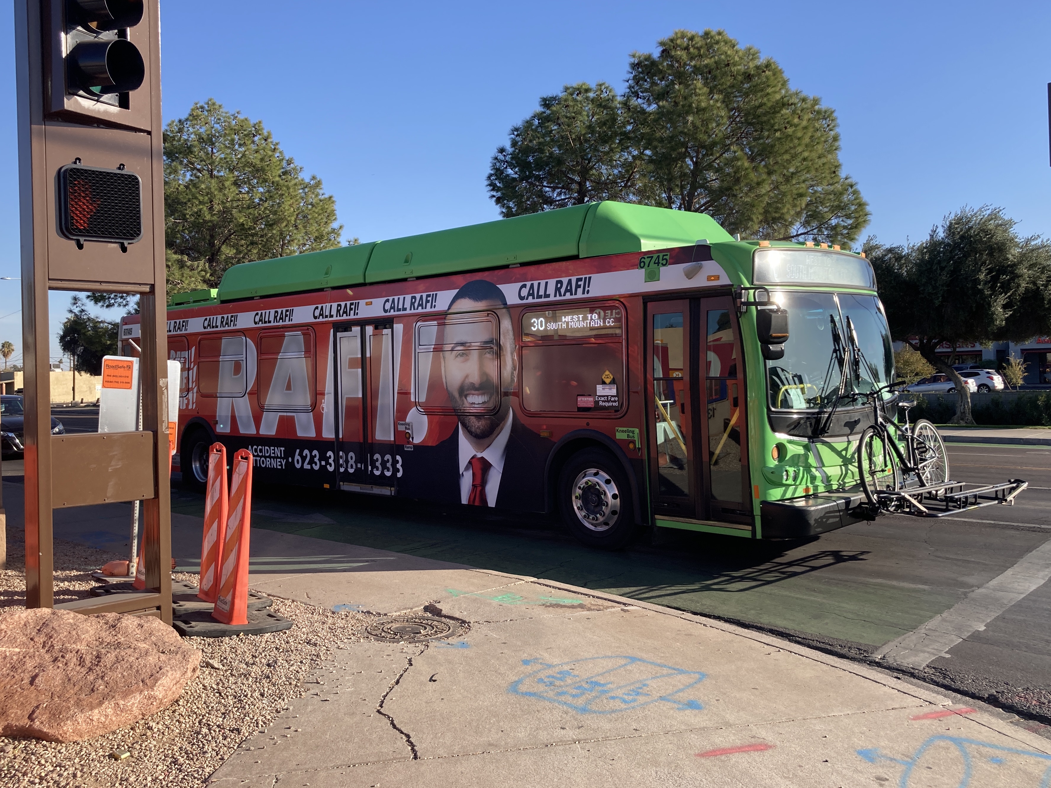 A green and gray Valley Metro bus, with a purple stripe, number 6745, traveling westbound on University Drive in Tempe on route 30 to South Mountain Community College