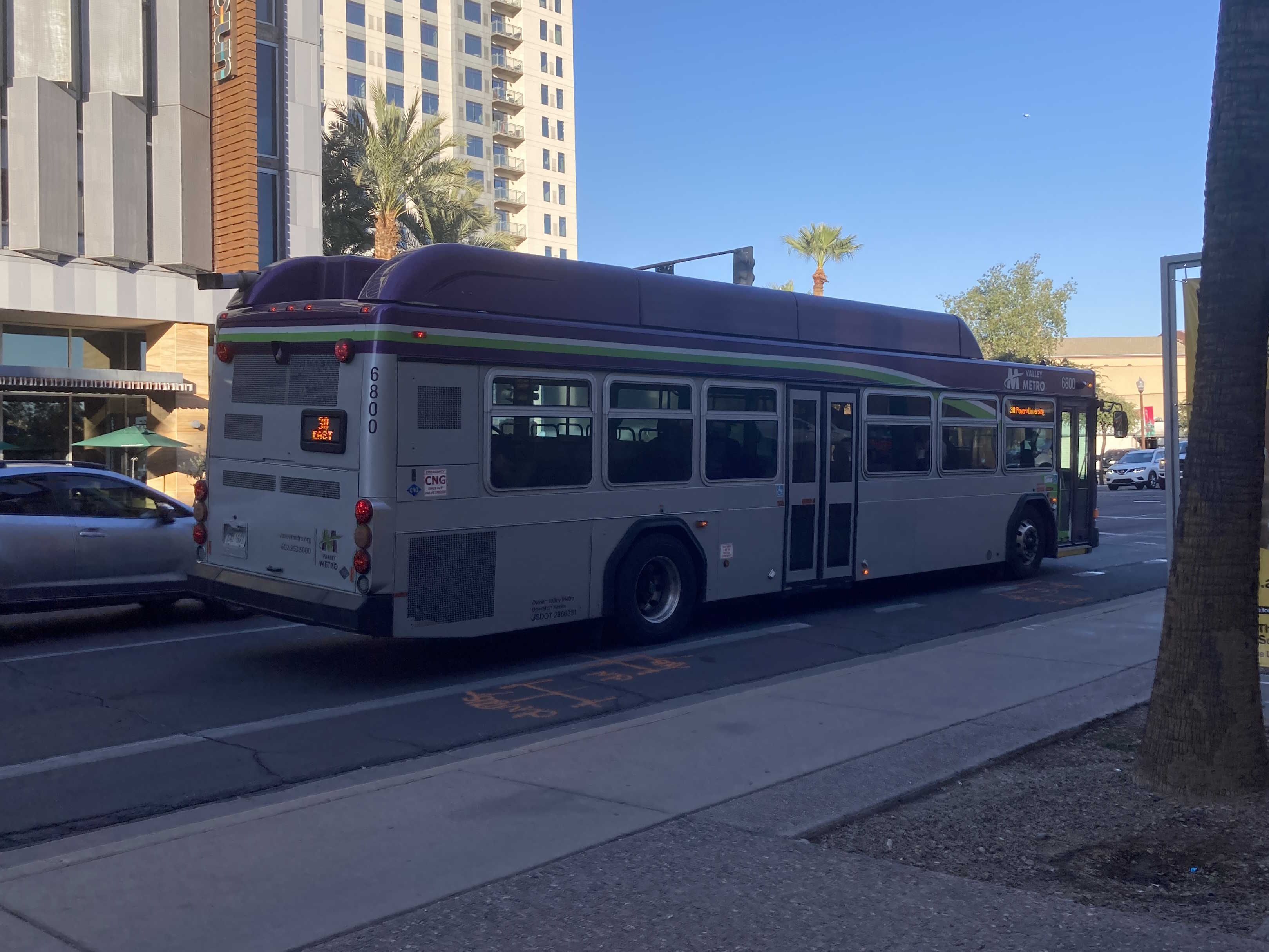 A gray and purple Valley Metro bus, with a white and green stripe, number 6800, traveling eastbound on University Drive in Tempe on route 30 to Power Road and University Drive