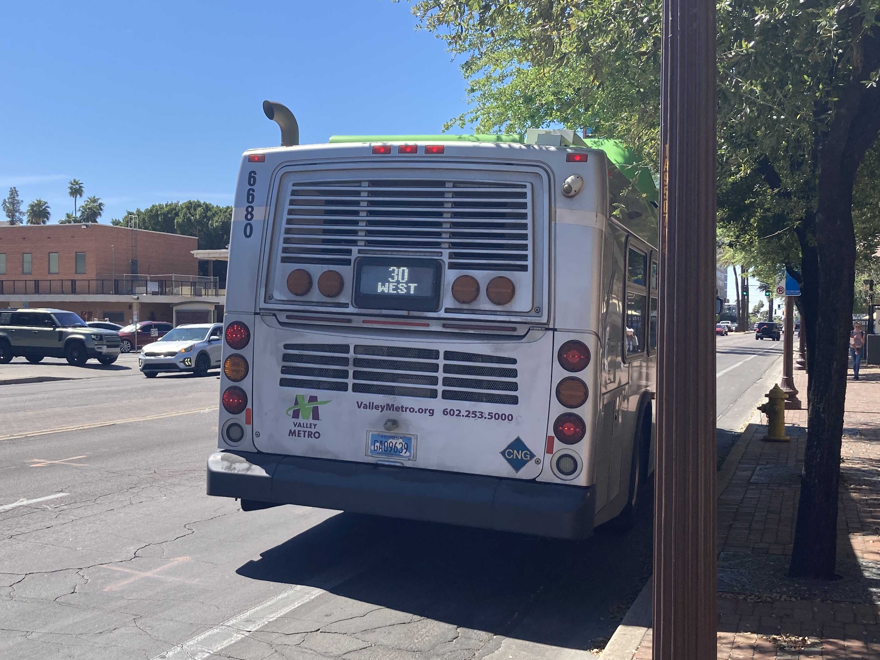 A green and gray Valley Metro bus, with a purple stripe, number 6680, traveling westbound on University Drive in Tempe on route 30 to South Mountain Community College