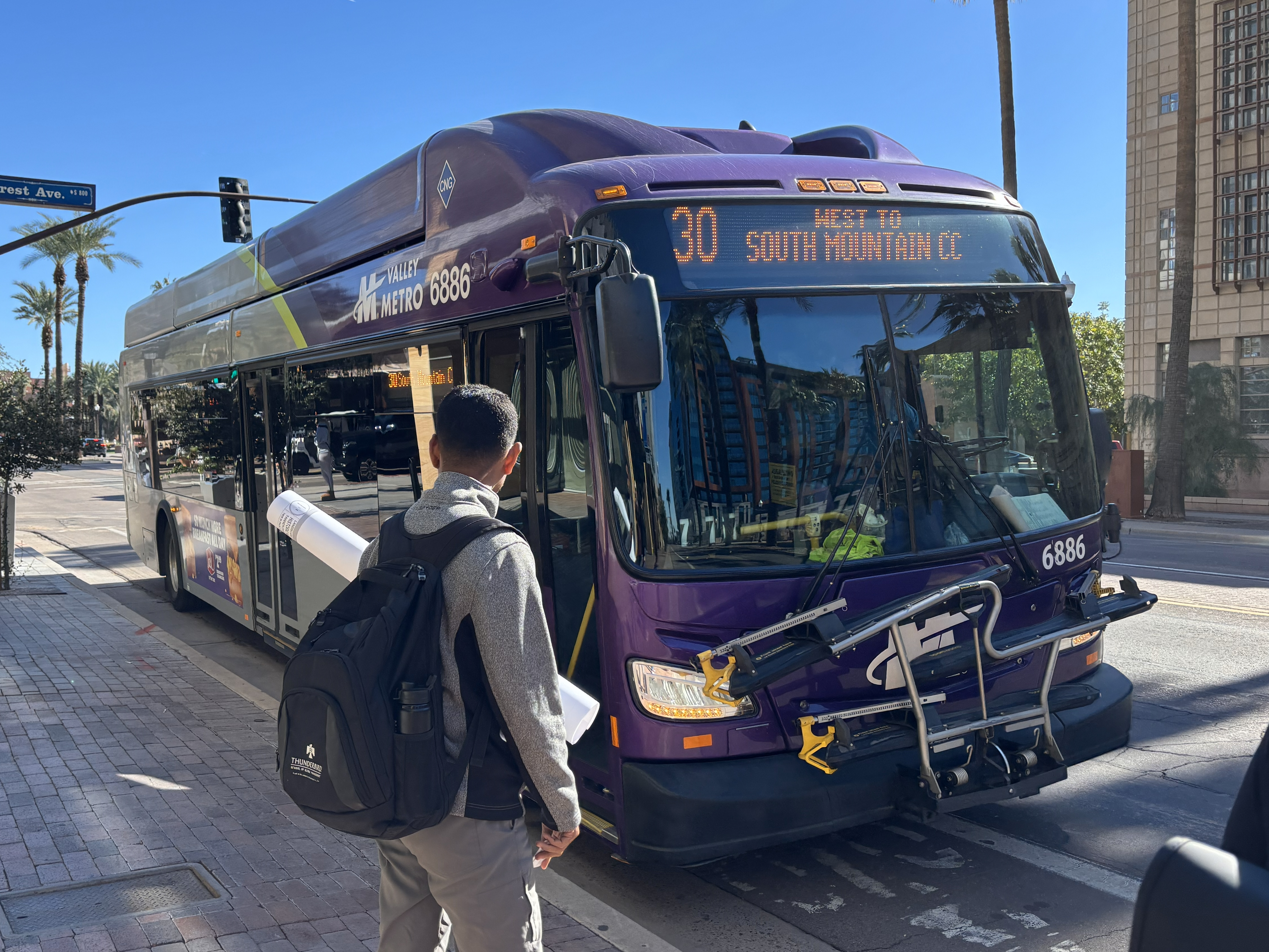 A gray and purple Valley Metro bus, with a green stripe, number 6886, traveling westbound on University Drive in Tempe on route 30 to South Mountain Community College