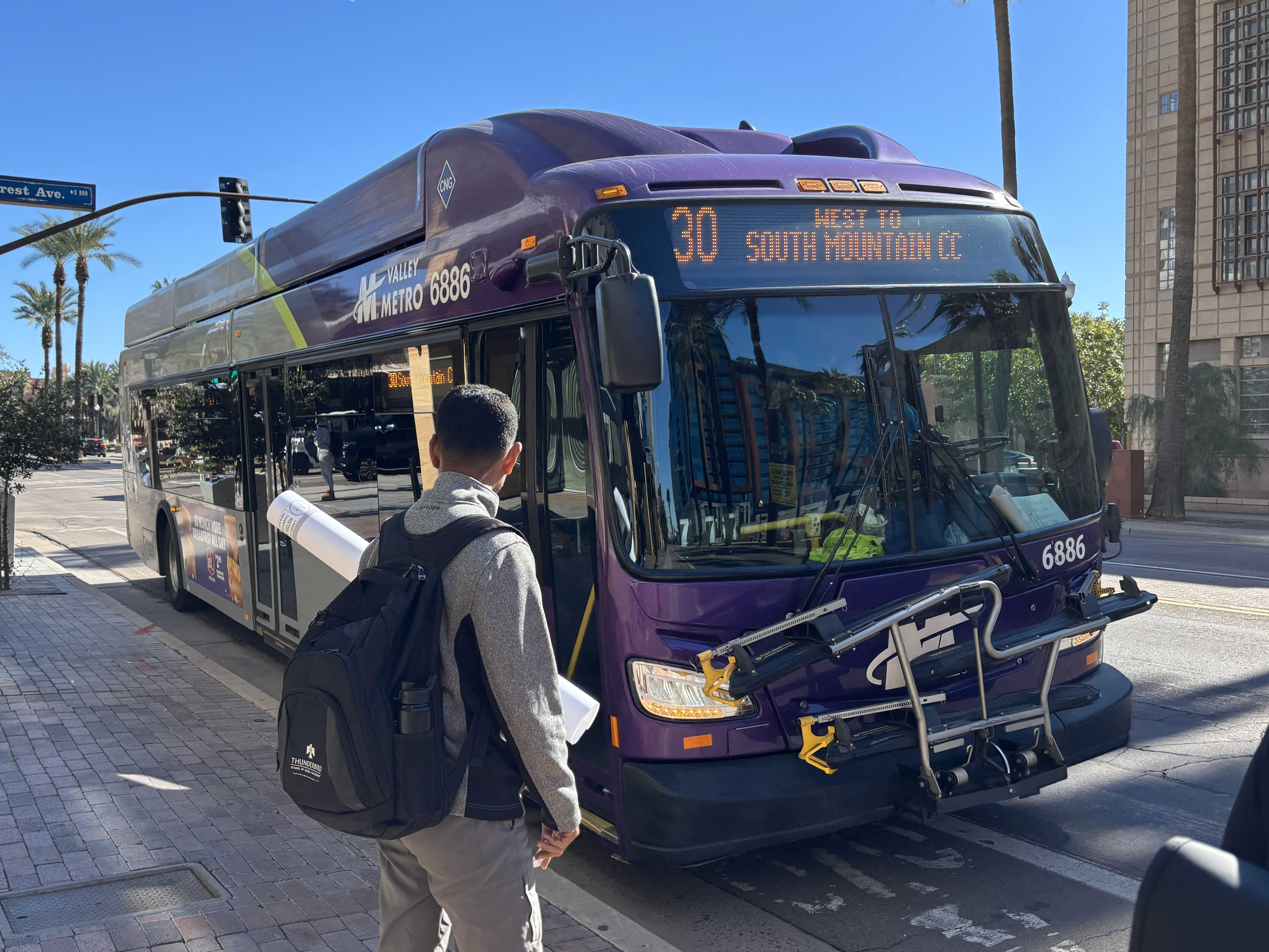 A gray and purple Valley Metro bus, with a green stripe, number 6886, traveling westbound on University Drive in Tempe on route 30 to South Mountain Community College