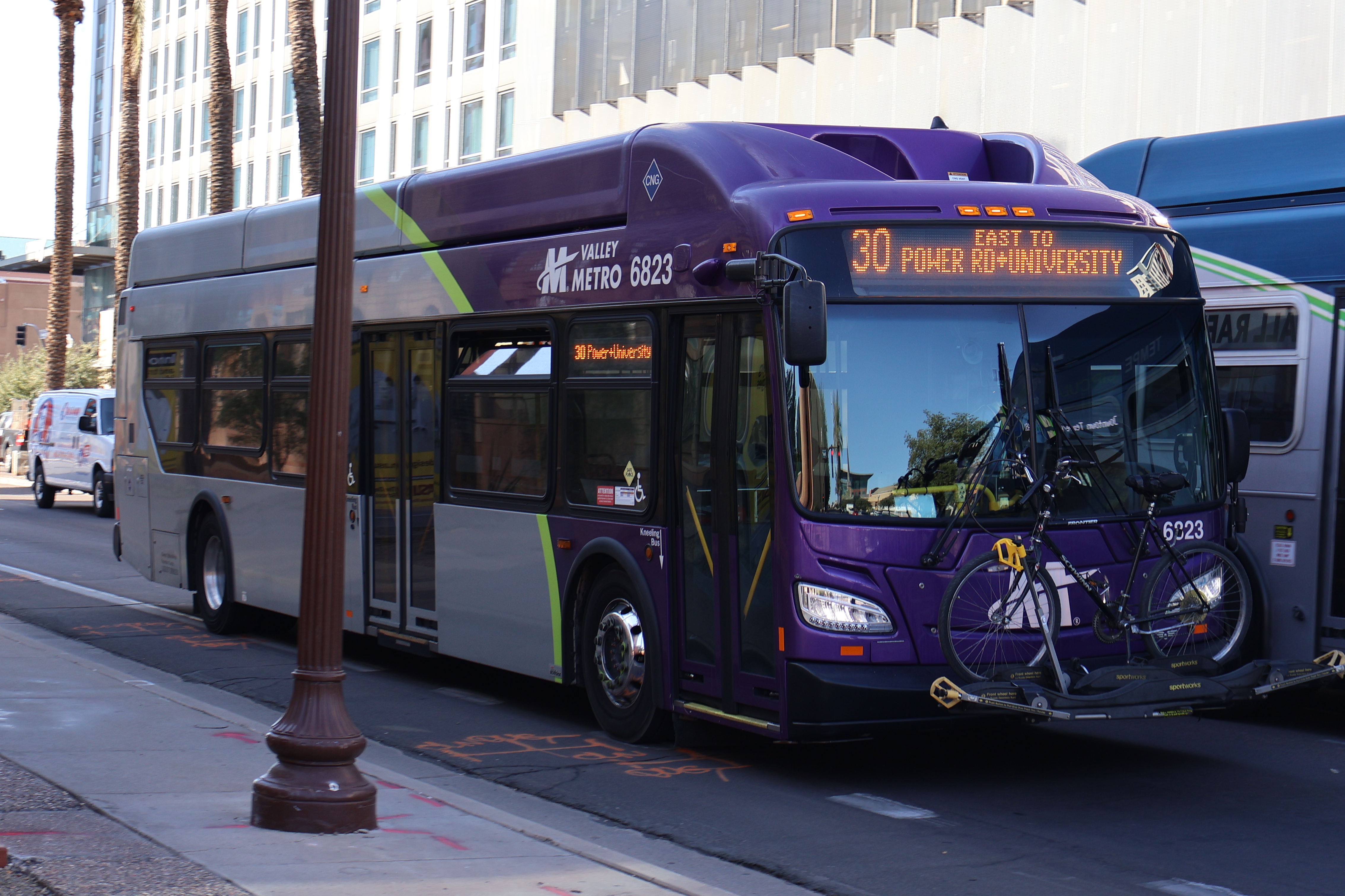 A gray and purple Valley Metro bus, with a green stripe, number 6823, traveling eastbound on University Drive in Tempe on route 30 to Power Road and University Drive