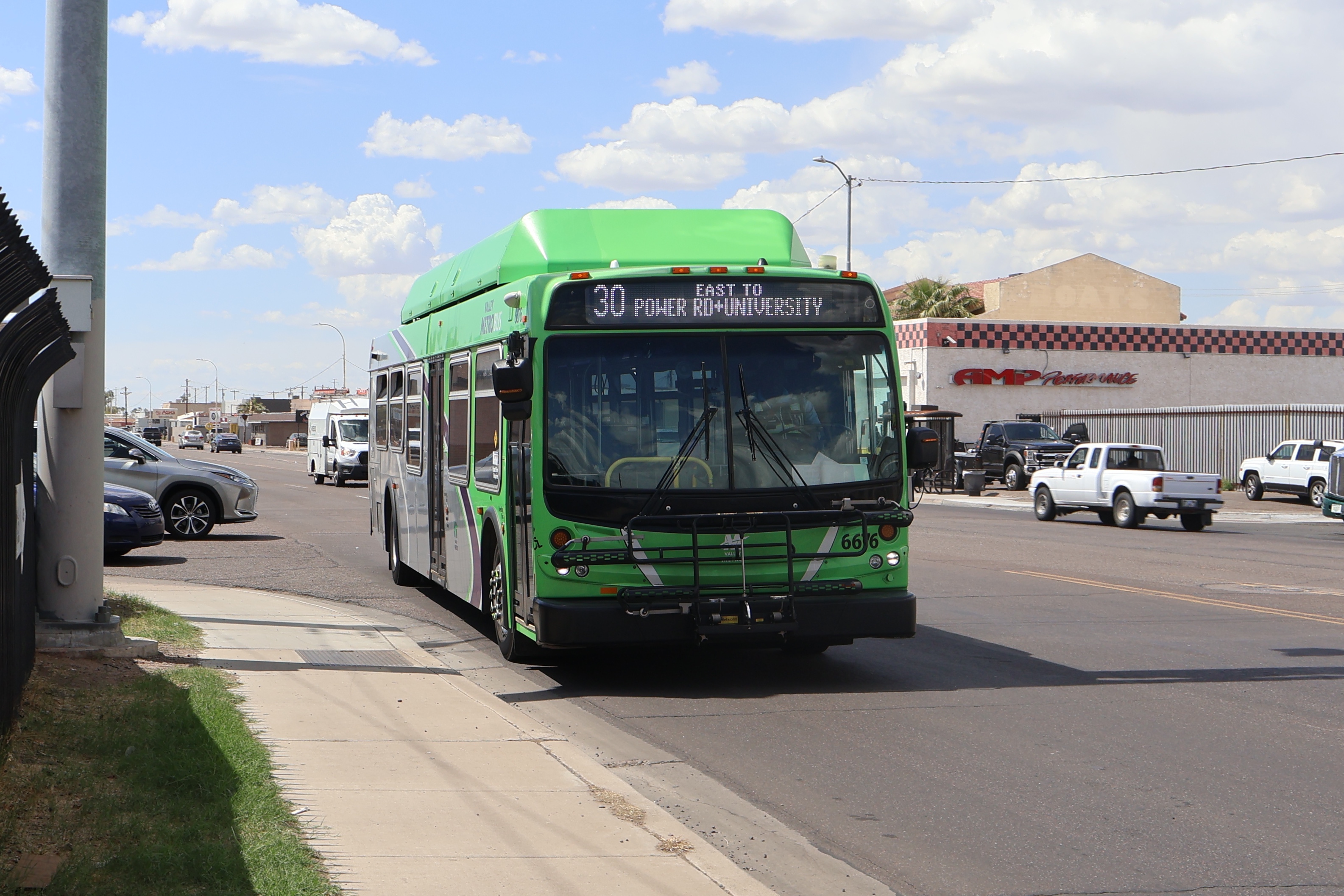 A green and gray Valley Metro bus, with a purple stripe, number 6676, traveling eastbound on University Drive in Phoenix on route 30 to Power Road and University Drive